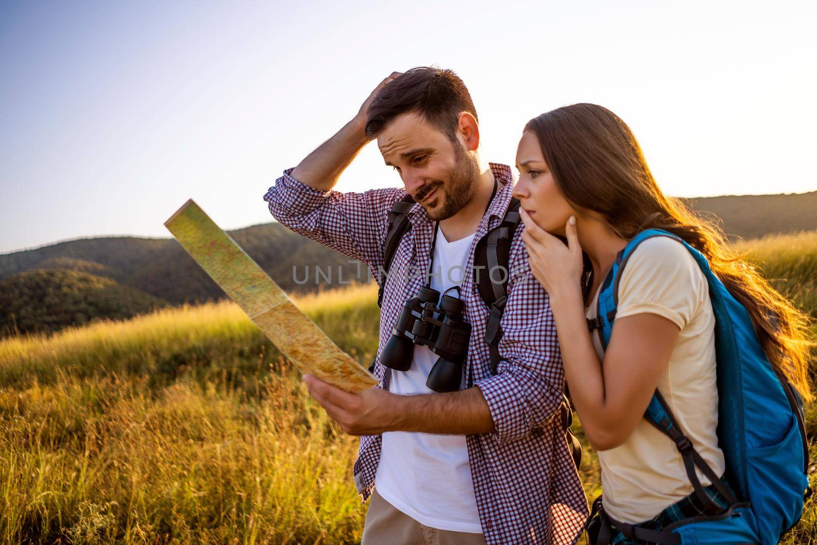 Couple is hiking in mountain. They are looking at map.