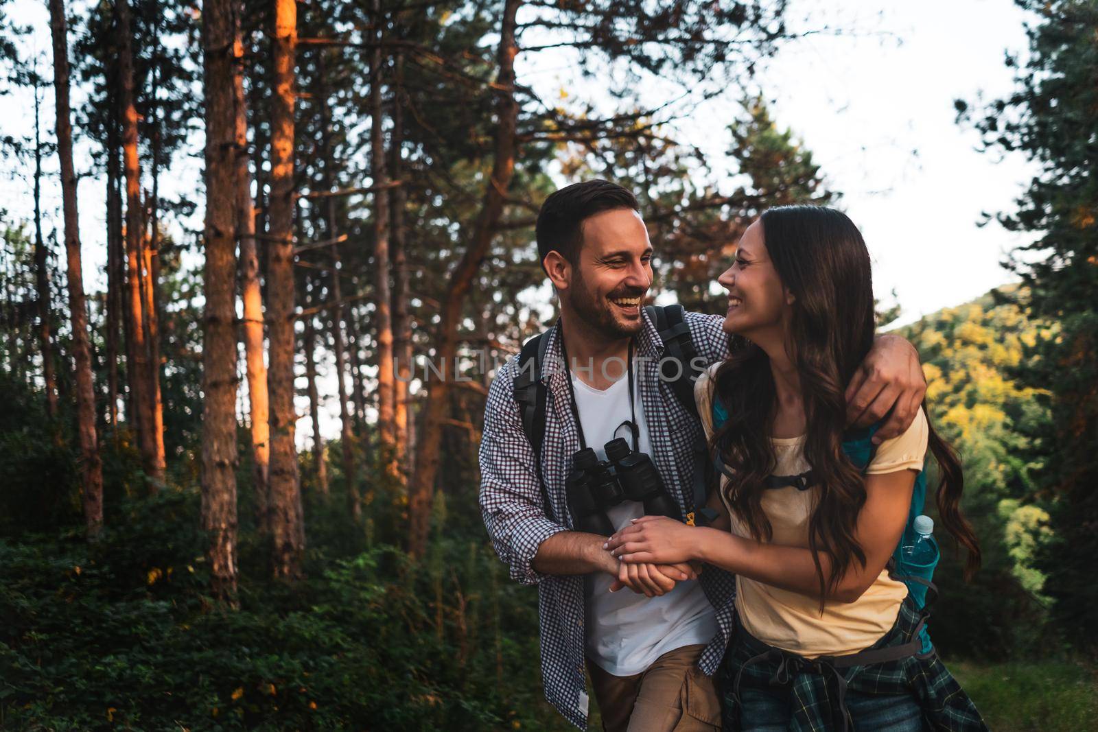 Happy couple is hiking in forest.