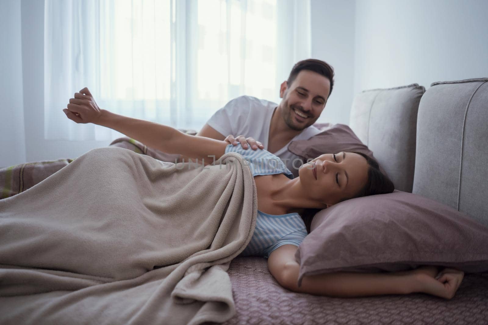 Young couple is lying in bed and waking up in the morning.