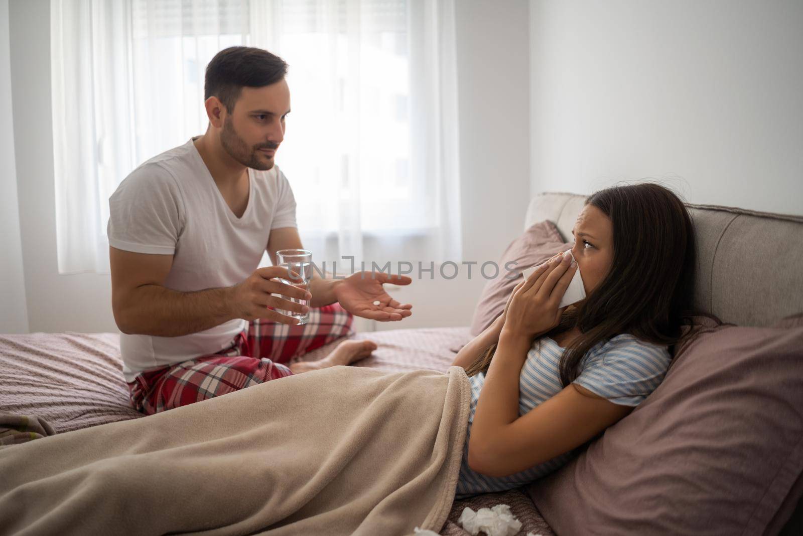 Woman is sick, man is giving her pills.