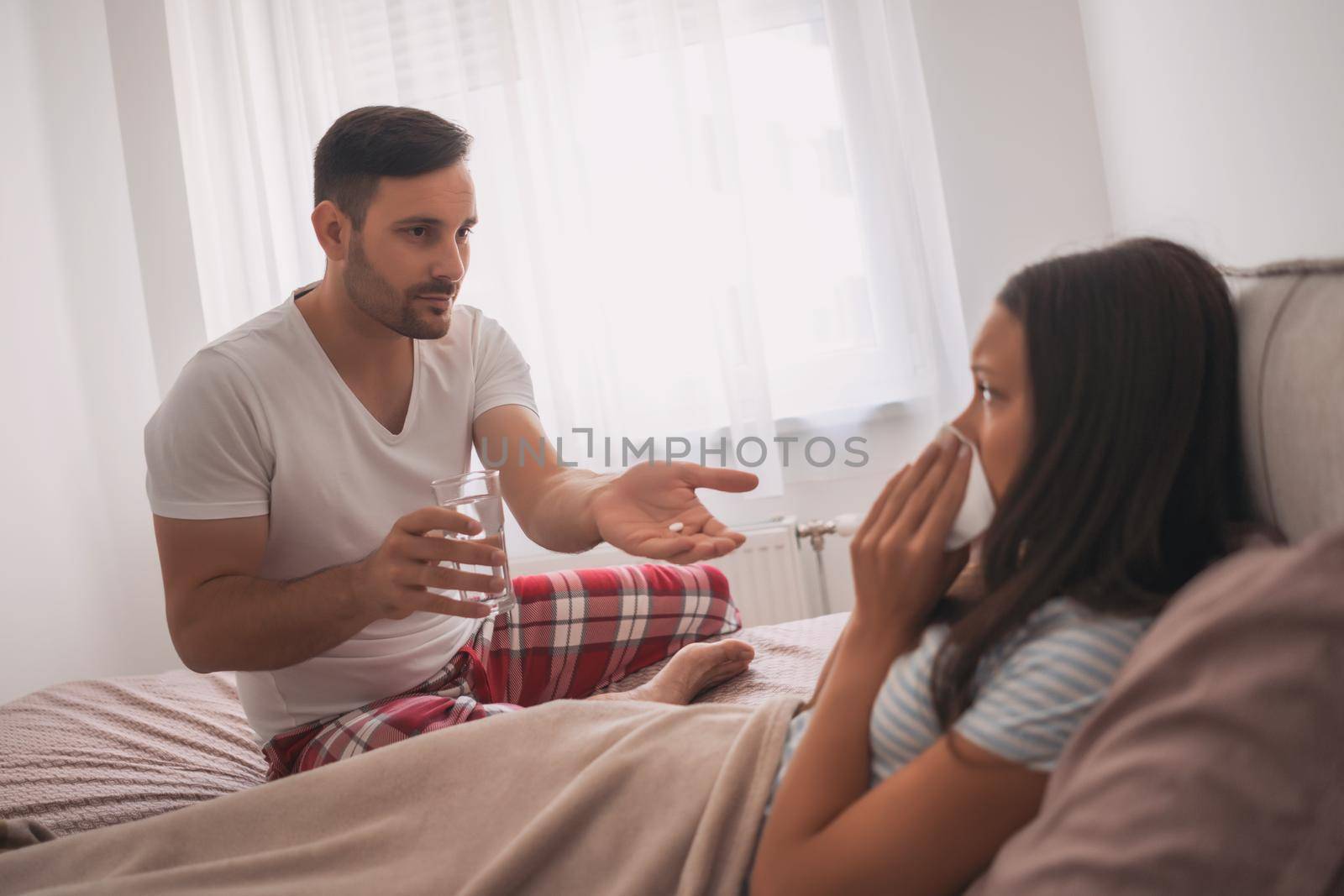 Woman is sick, man is giving her pills.