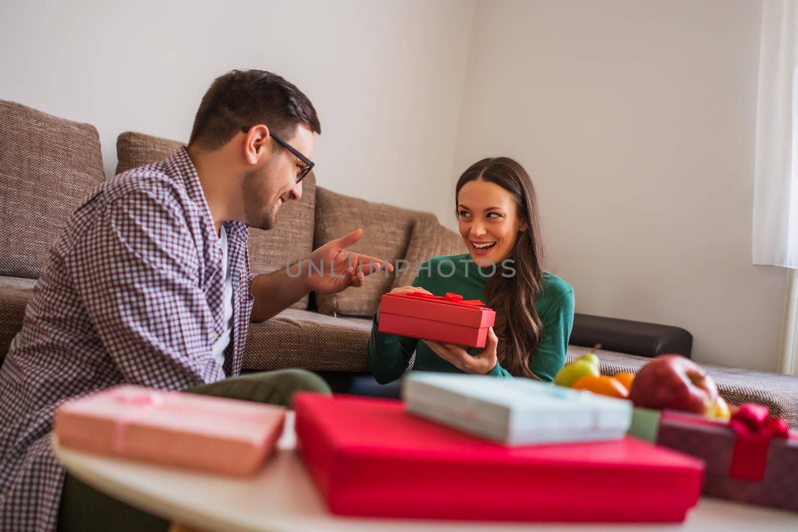 Happy couple is sharing gifts in their home.