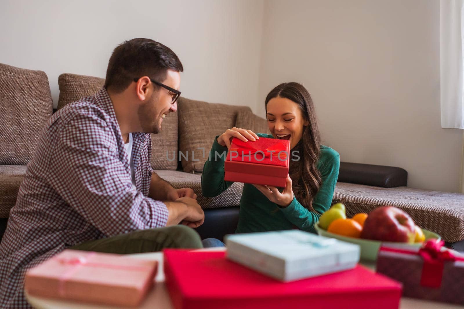 Happy couple is sharing gifts in their home.