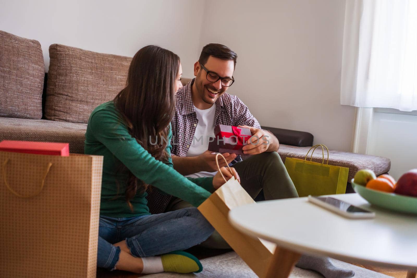 Happy couple is sharing gifts in their home.