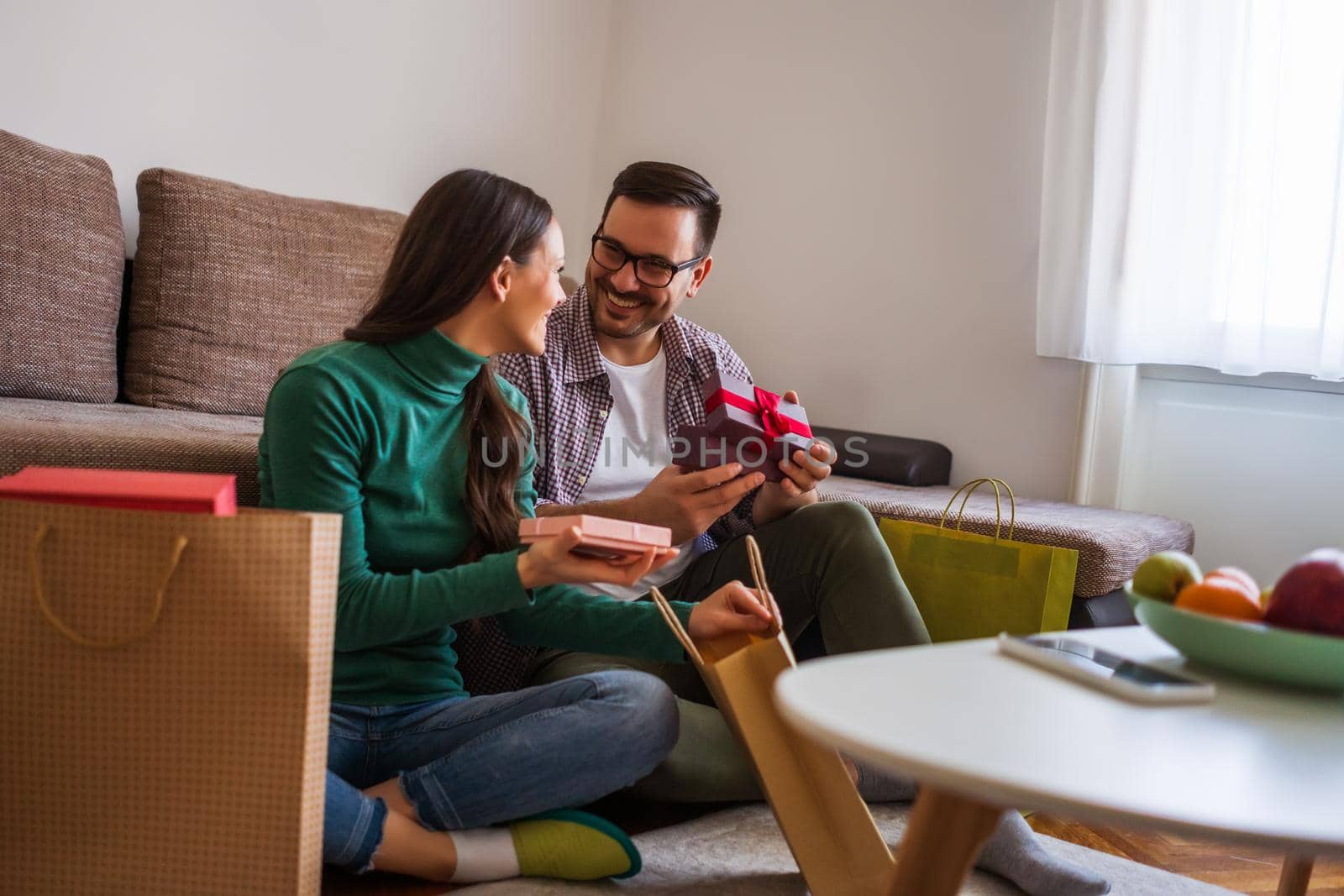 Happy couple is sharing gifts in their home.