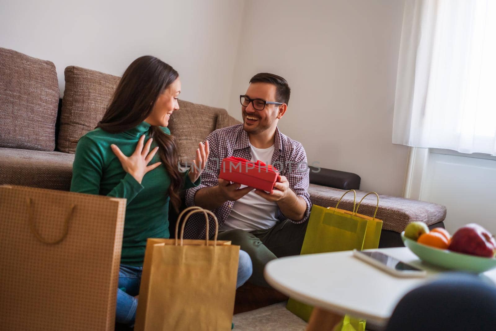 Happy couple is sharing gifts in their home.