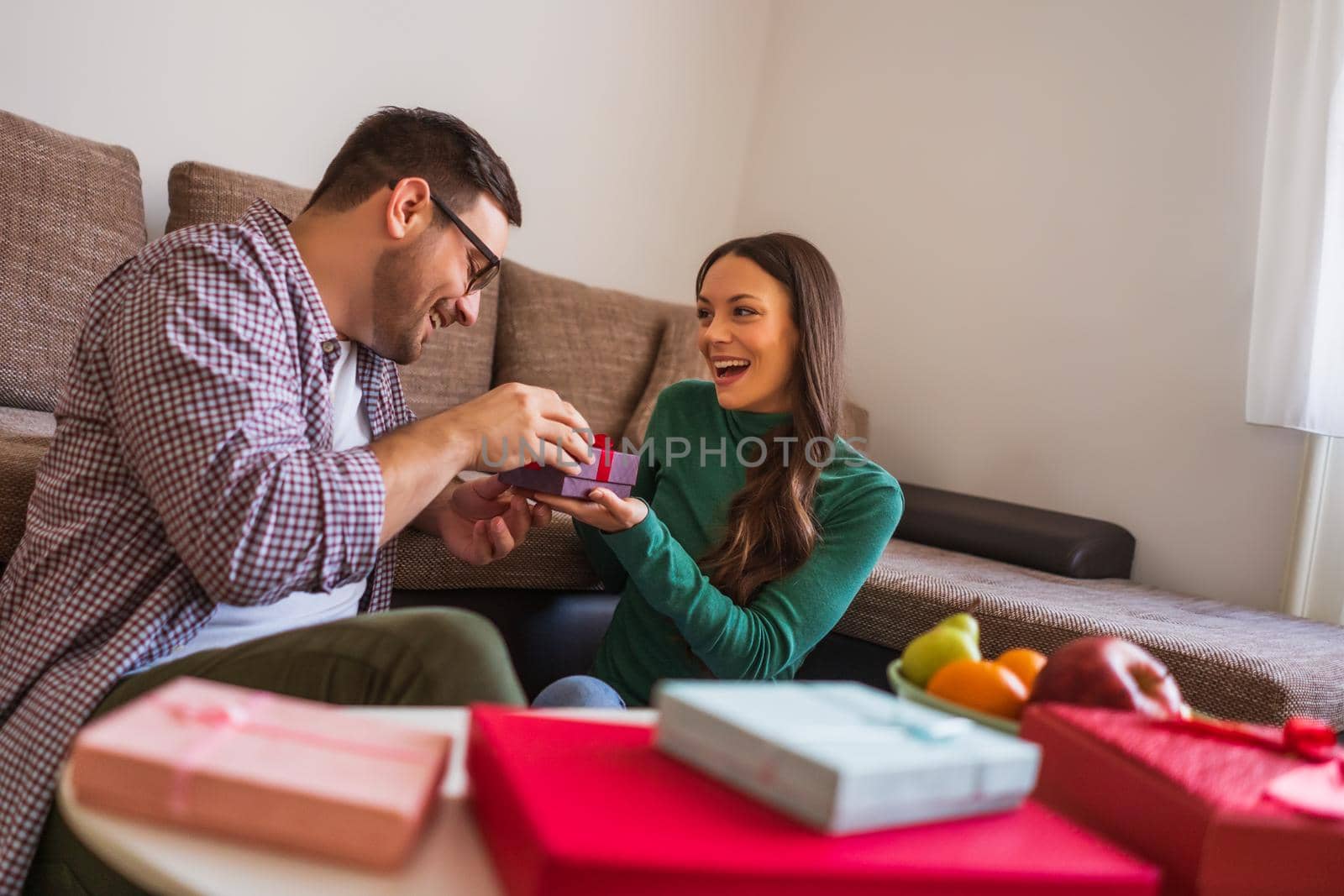 Happy couple is sharing gifts in their home.