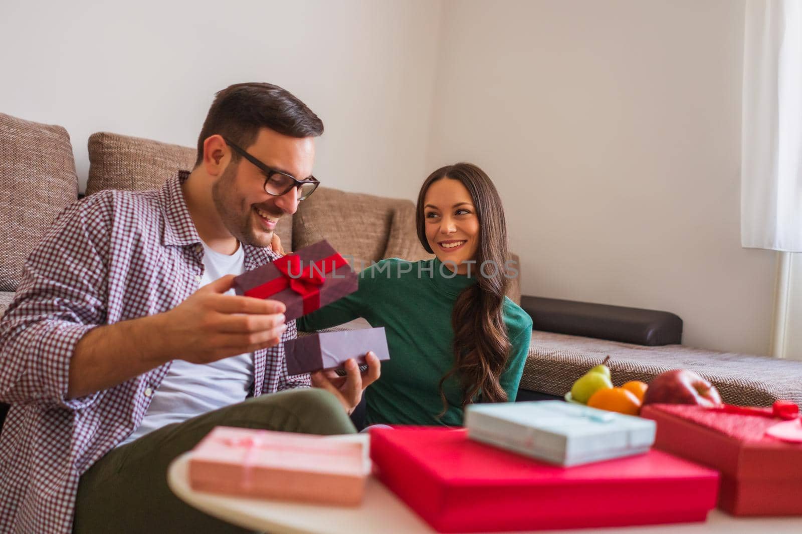 Happy couple is sharing gifts in their home.