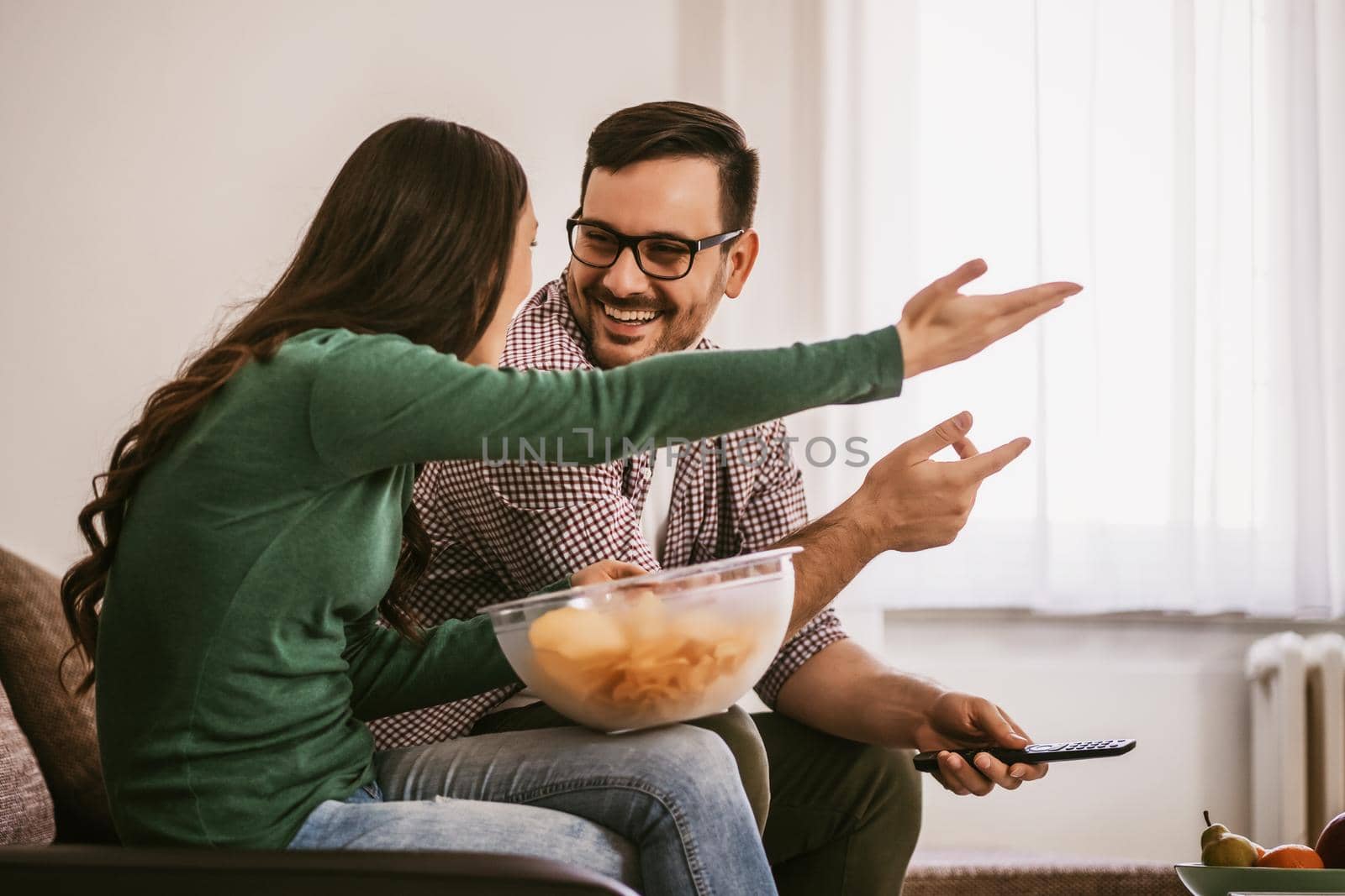 Couple is relaxing at home. They are watching tv.