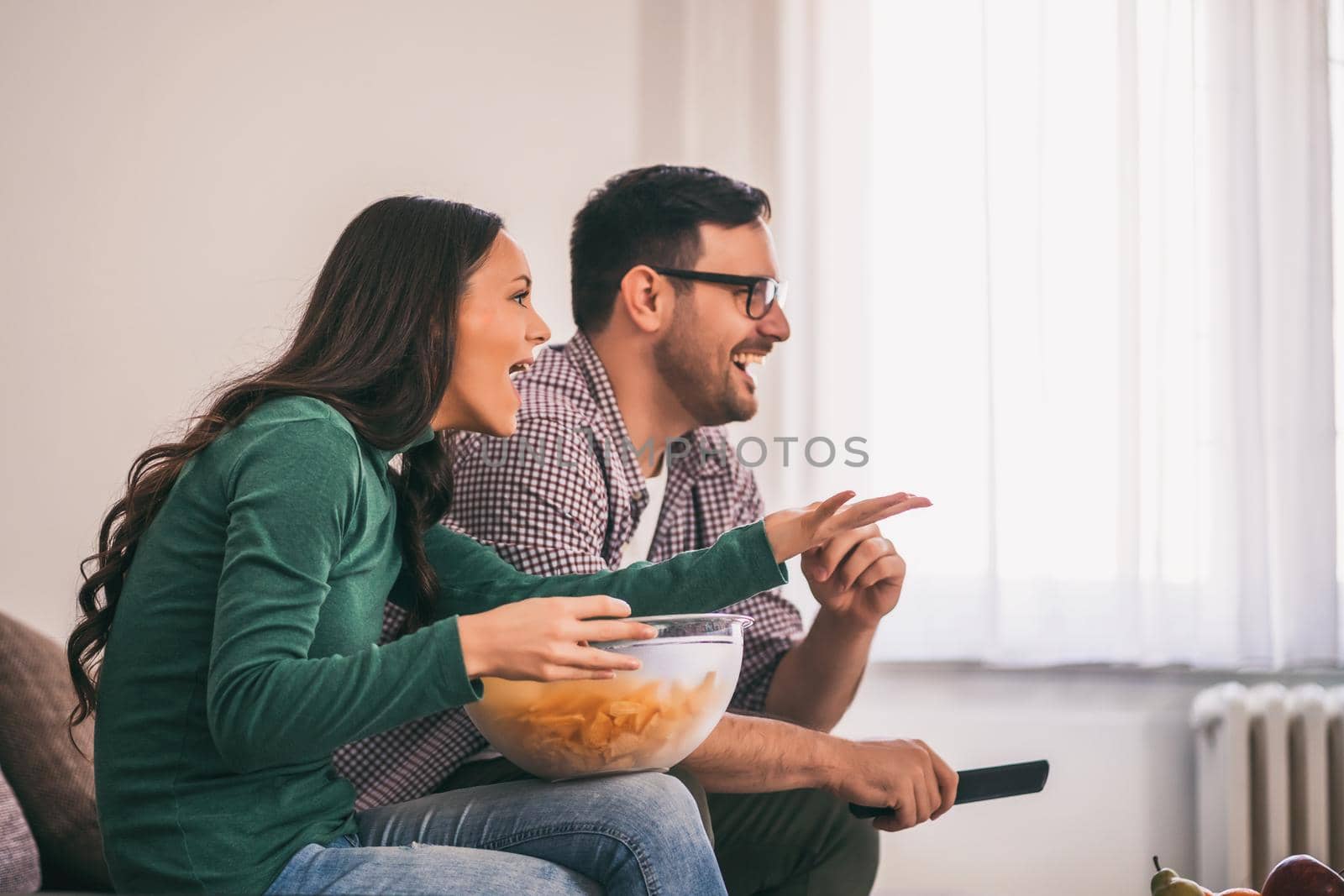 Couple is relaxing at home. They are watching tv.