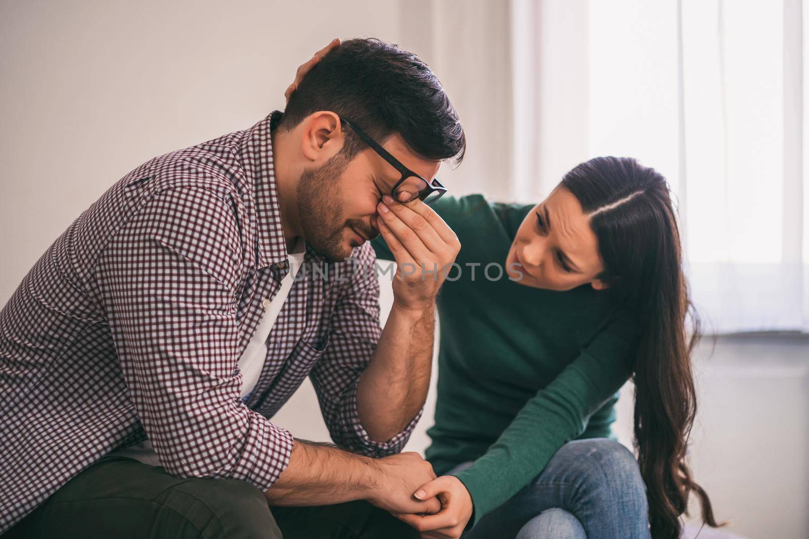 Man is sad and depressed, his wife is consoling him.