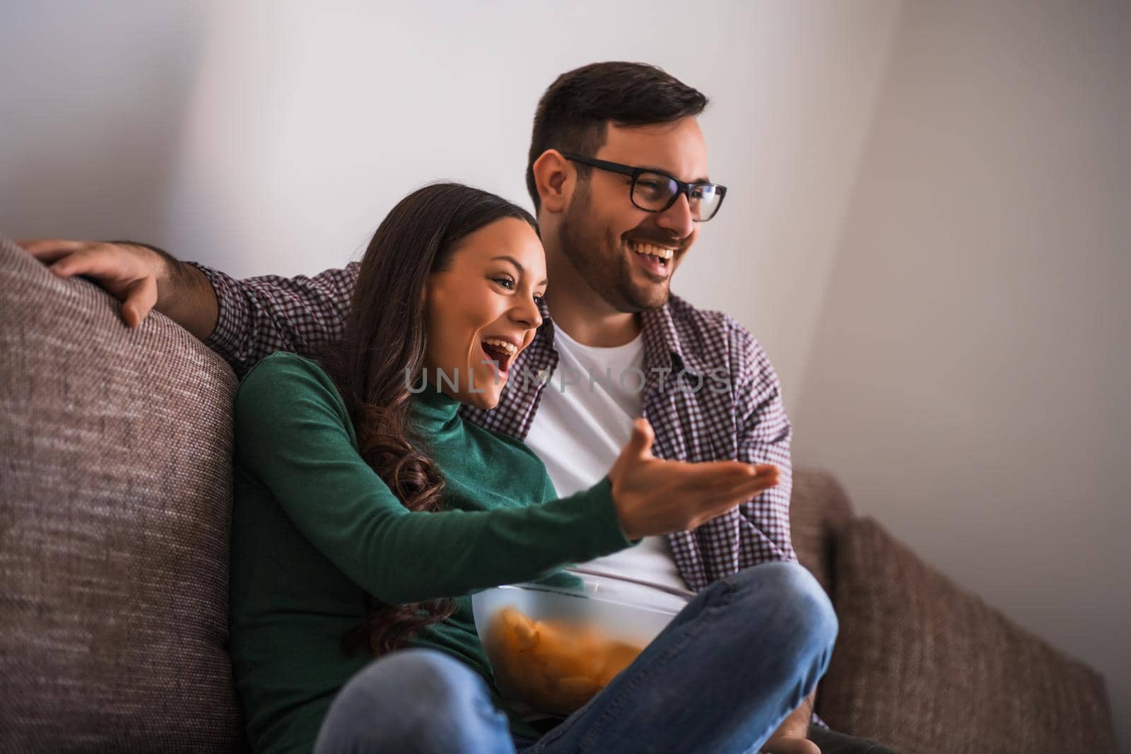 Couple is relaxing at home. They are watching tv.