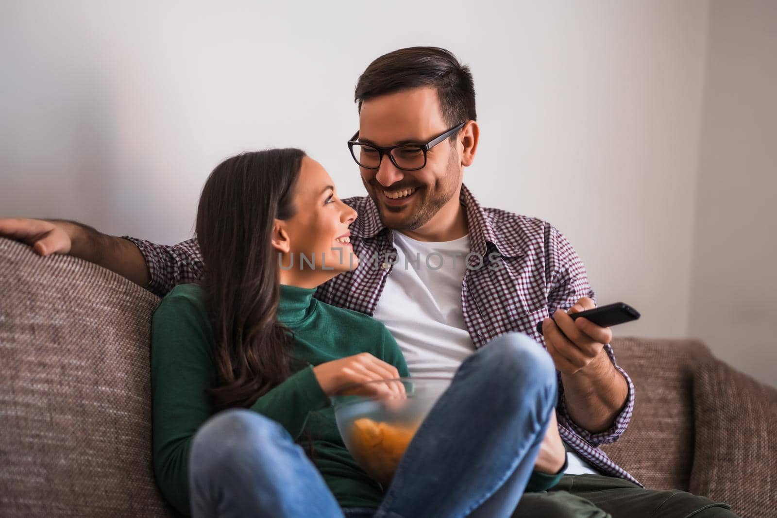 Couple is relaxing at home. They are watching tv.