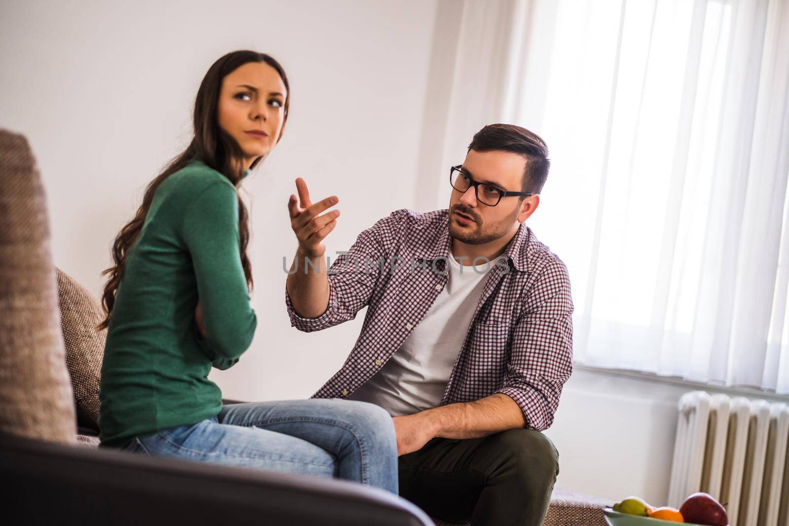 Man and woman are sitting at sofa and arguing. Relationship problems.