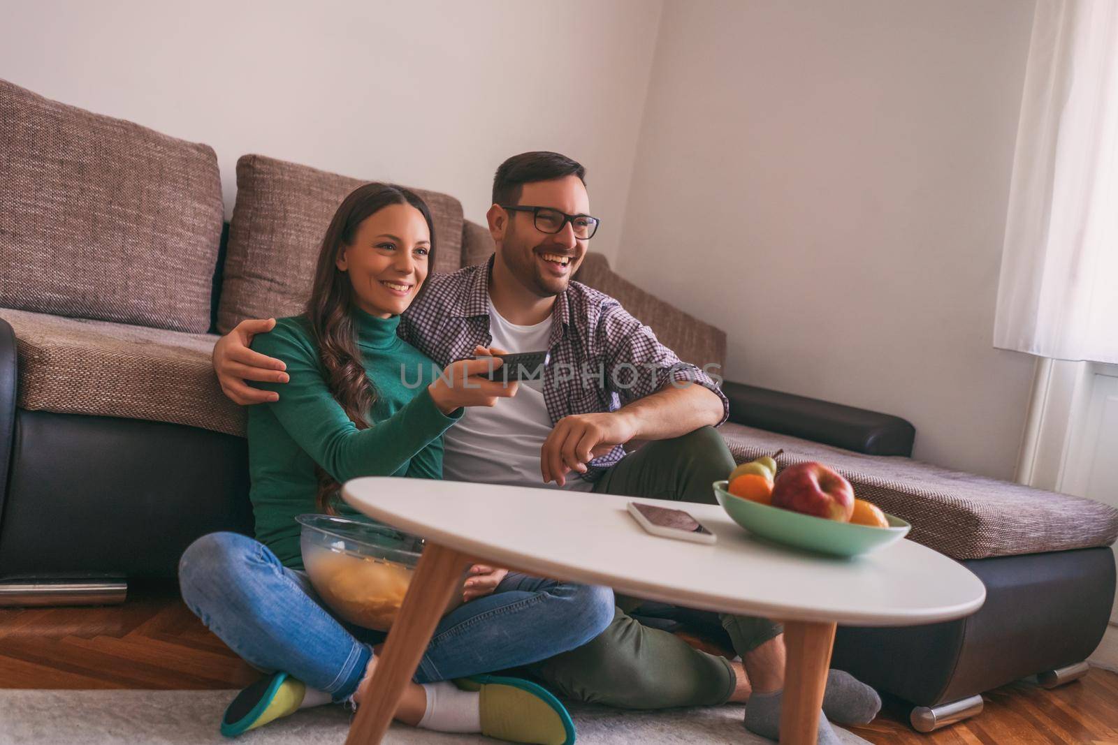 Couple is relaxing at home. They are watching tv.