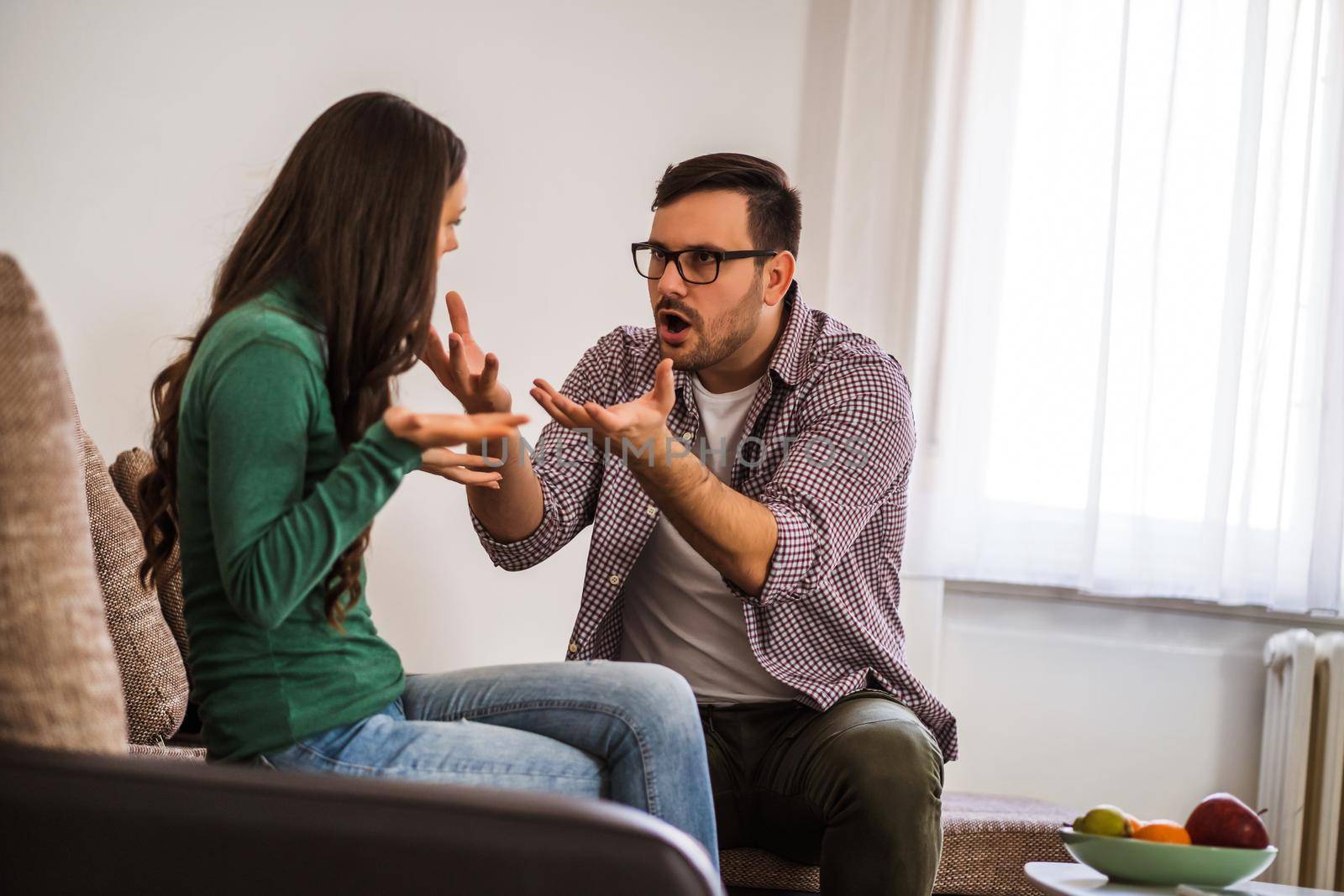 Man and woman are sitting at sofa and arguing. Relationship problems.