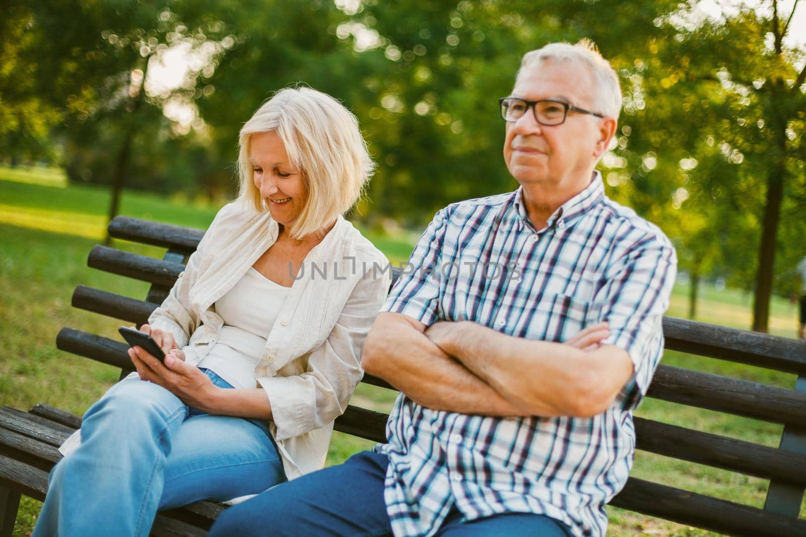 Senior man is angry while his woman is messaging on phone.