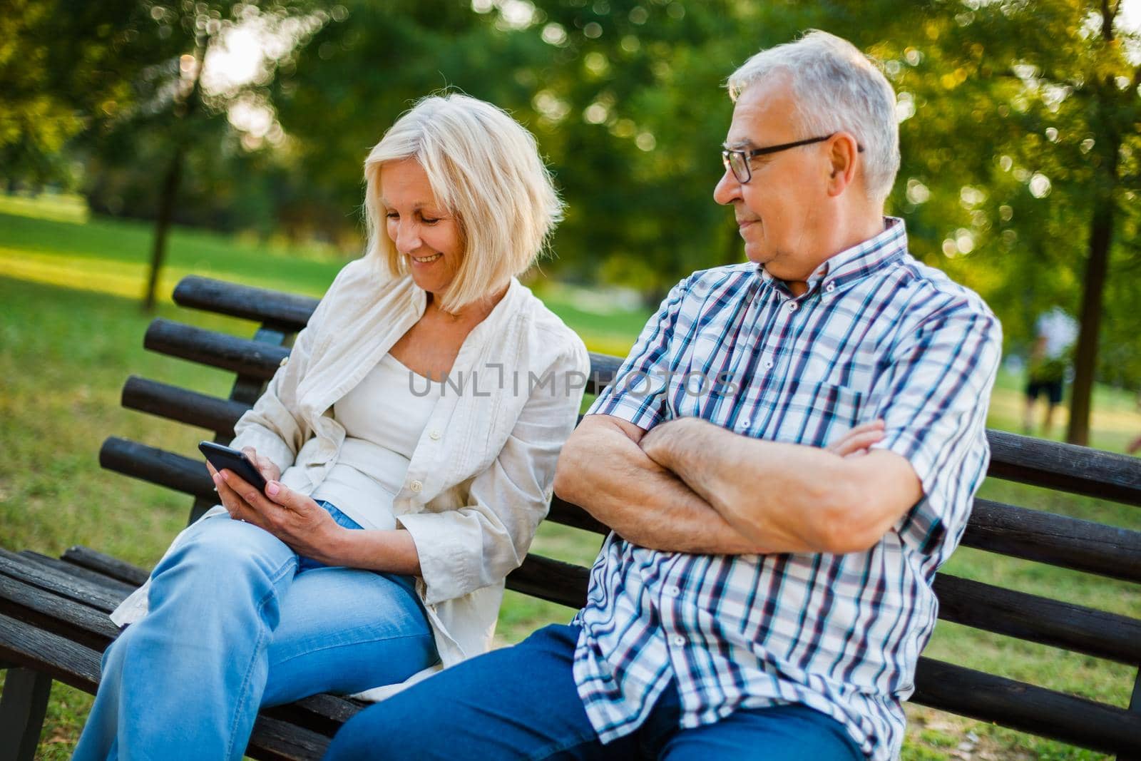 Senior man is angry while his woman is messaging on phone.