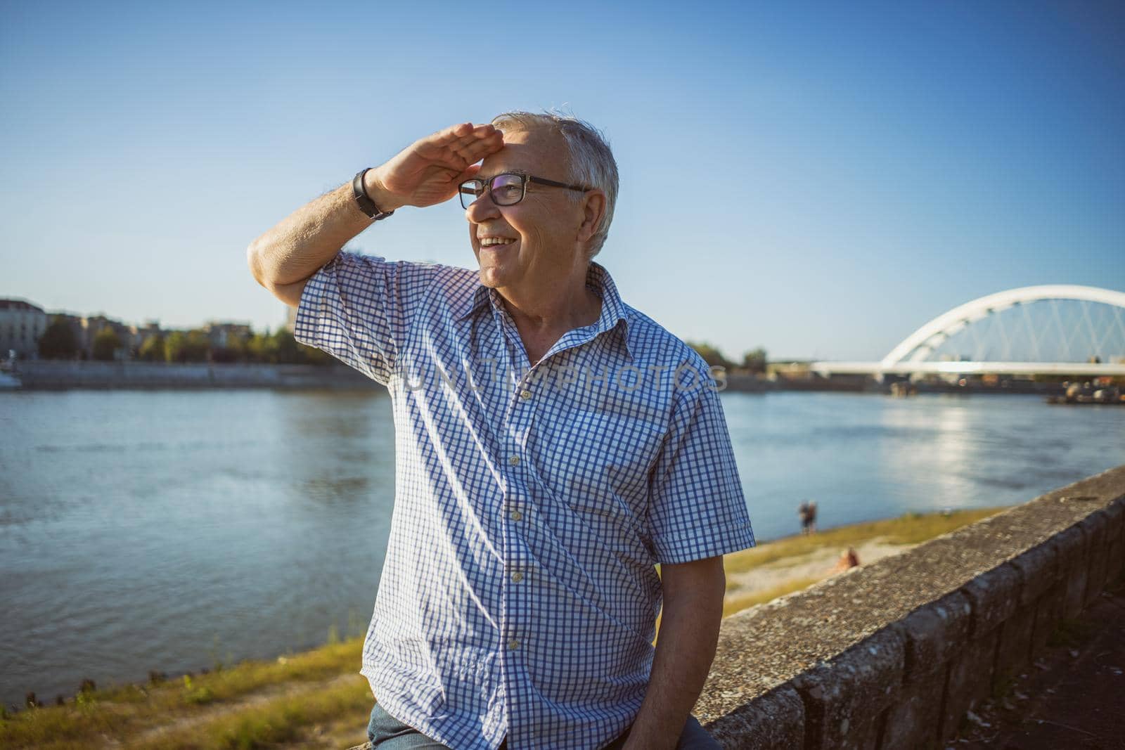 Outdoor portrait of happy senior man who is looking at distance.