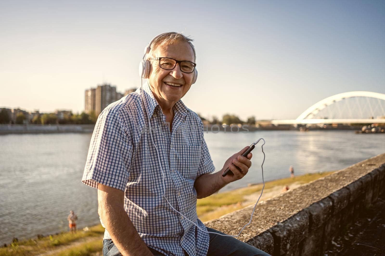 Outdoor portrait of senior man who is listening music on headphones.