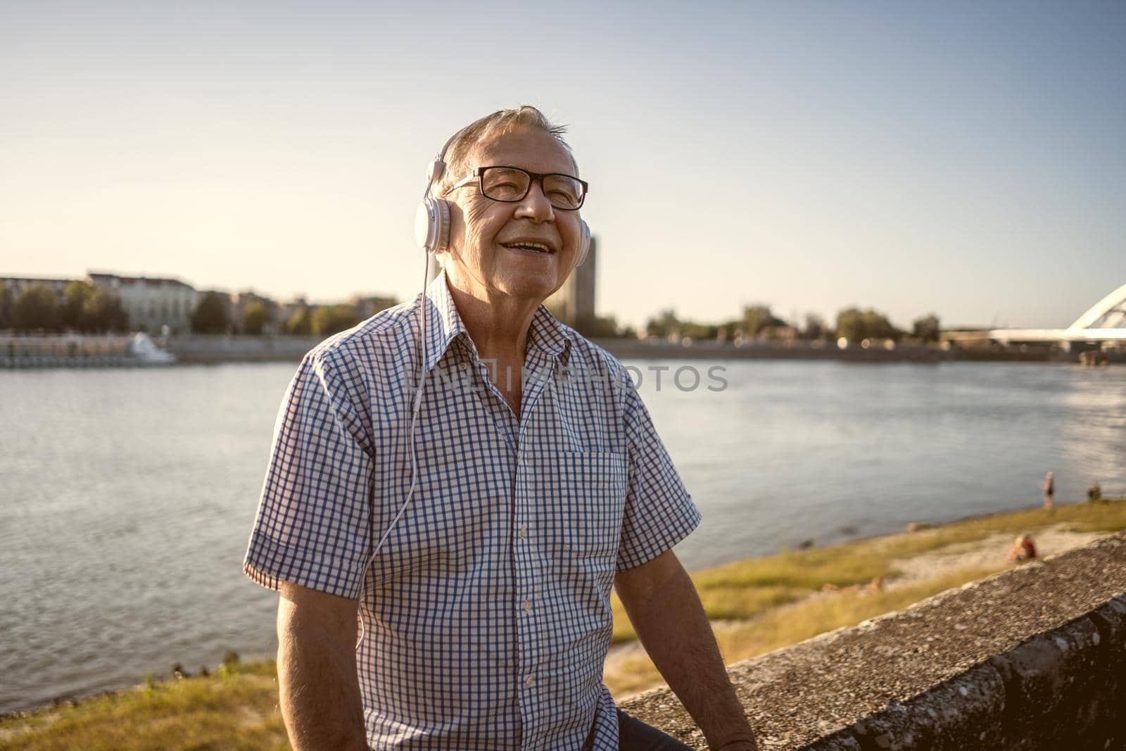 Outdoor portrait of senior man who is listening music on headphones.