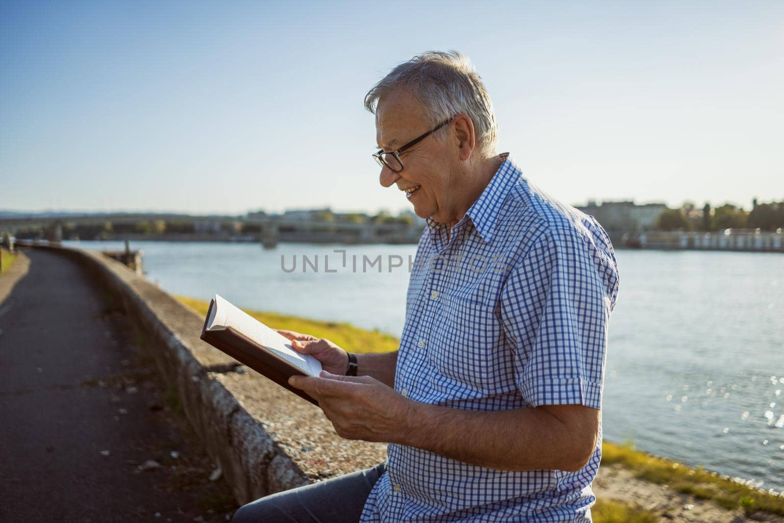 Outdoor portrait of senior man who is reading a book.