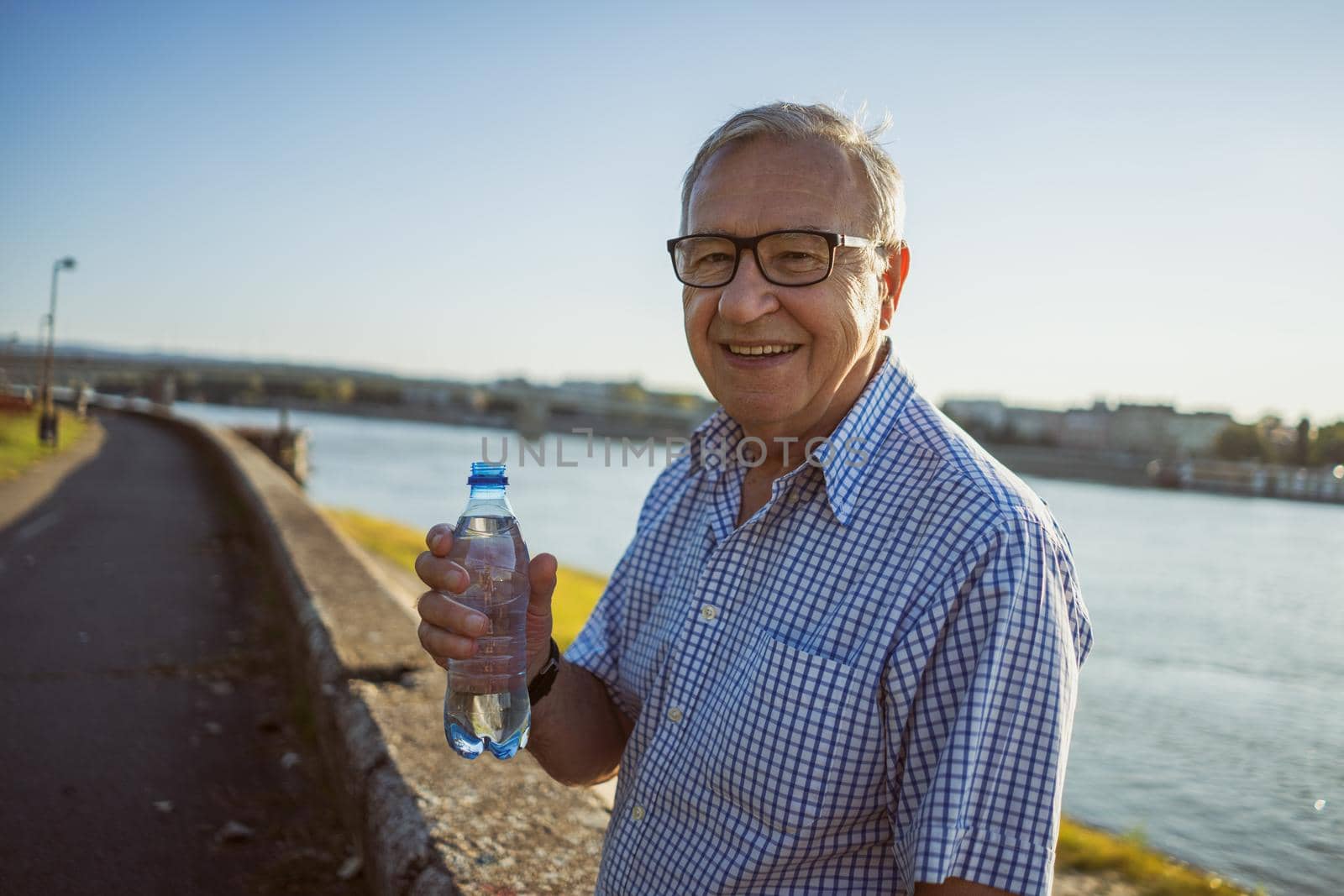 Outdoor portrait of senior man who is holding bottle of water.
