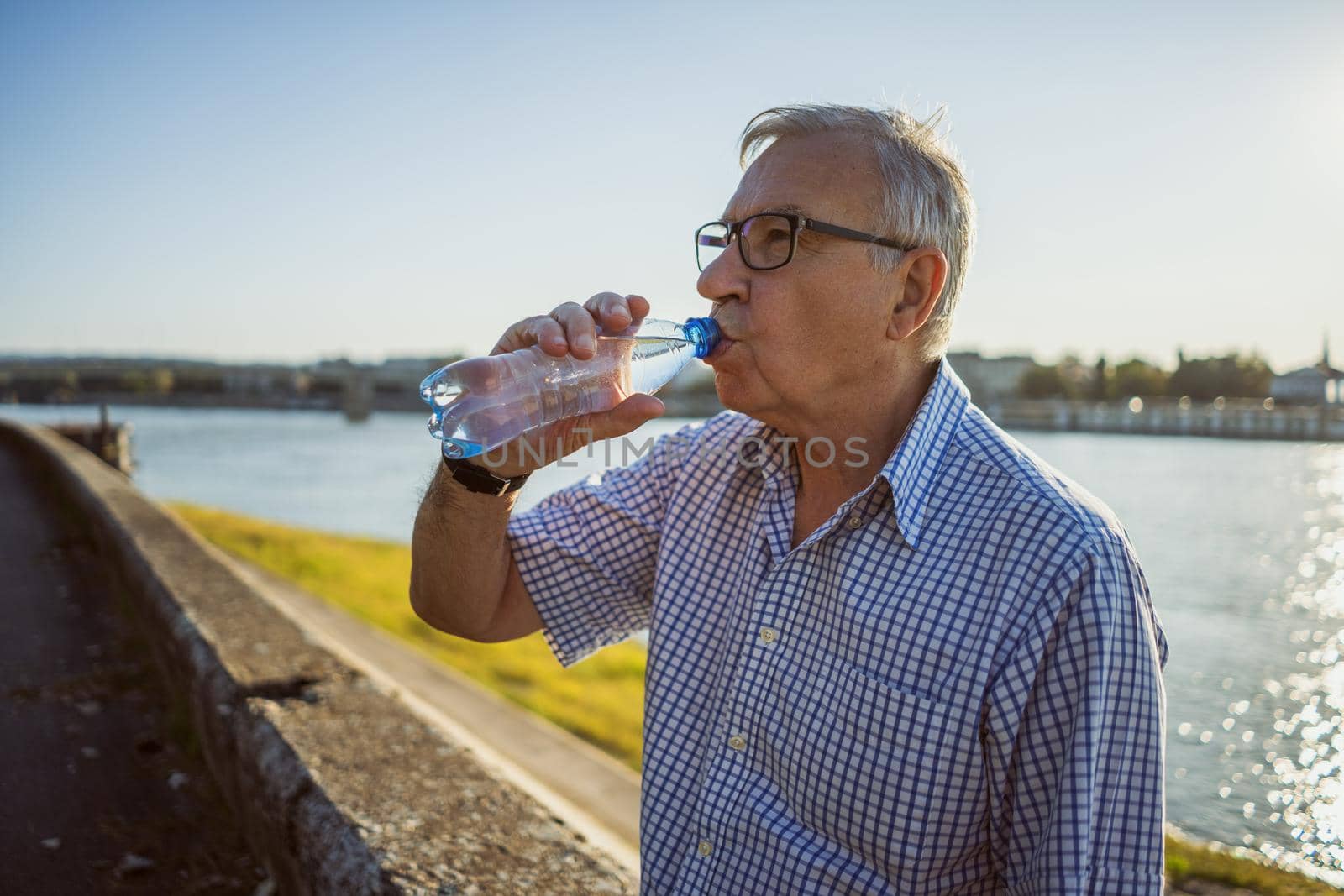 Outdoor portrait of senior man who is drinking water.