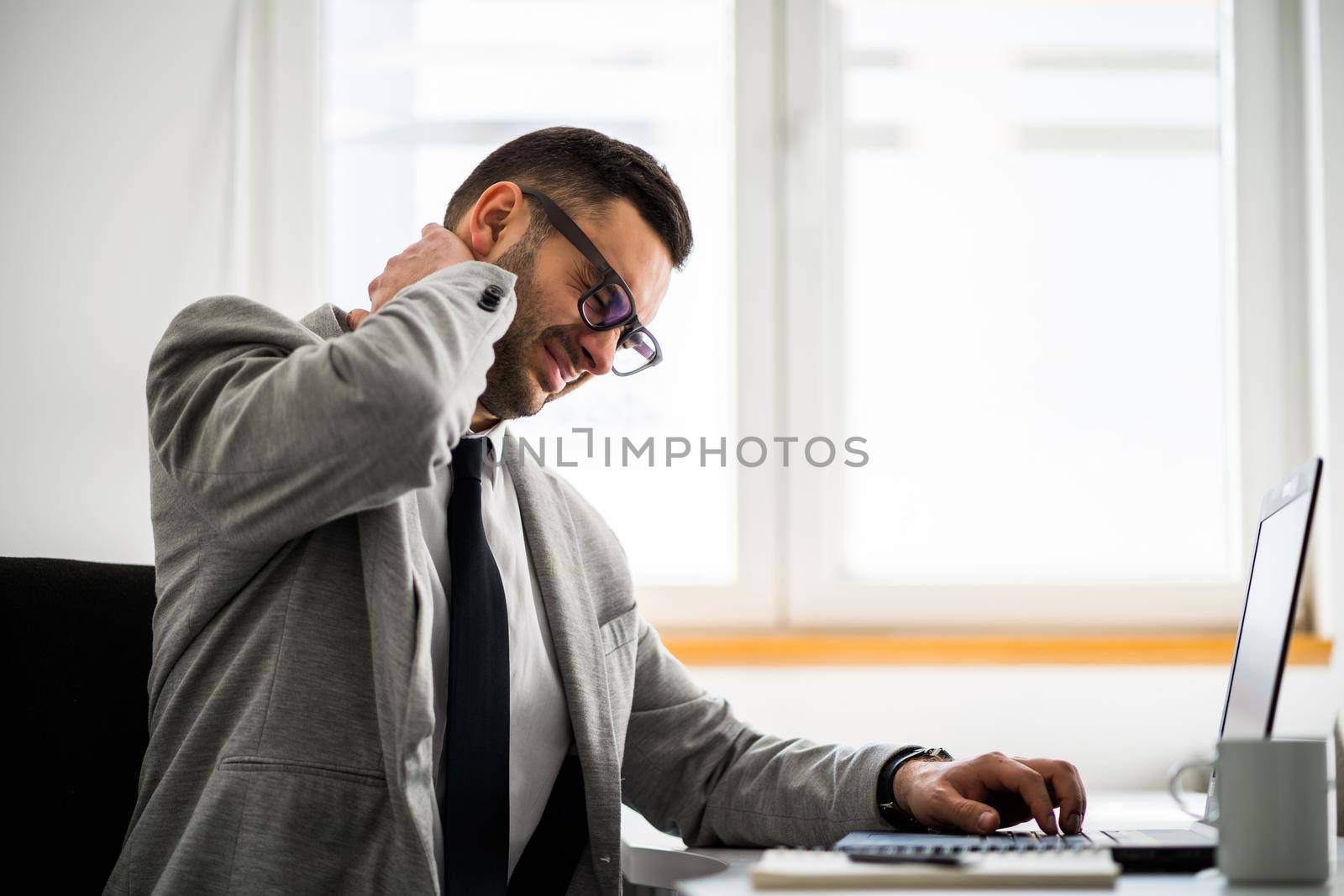 Young businessman is having pain in his neck and back.