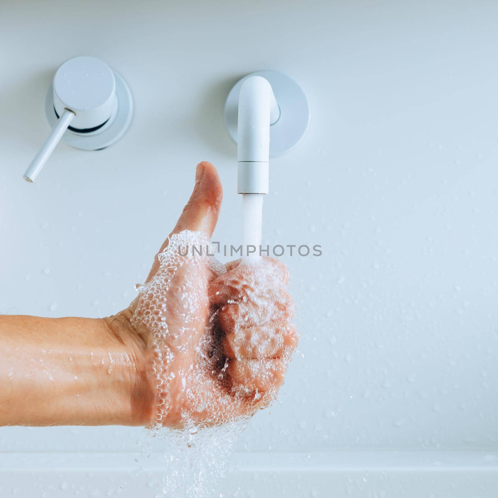 thumbs up hand under the mixer spout with flowing water