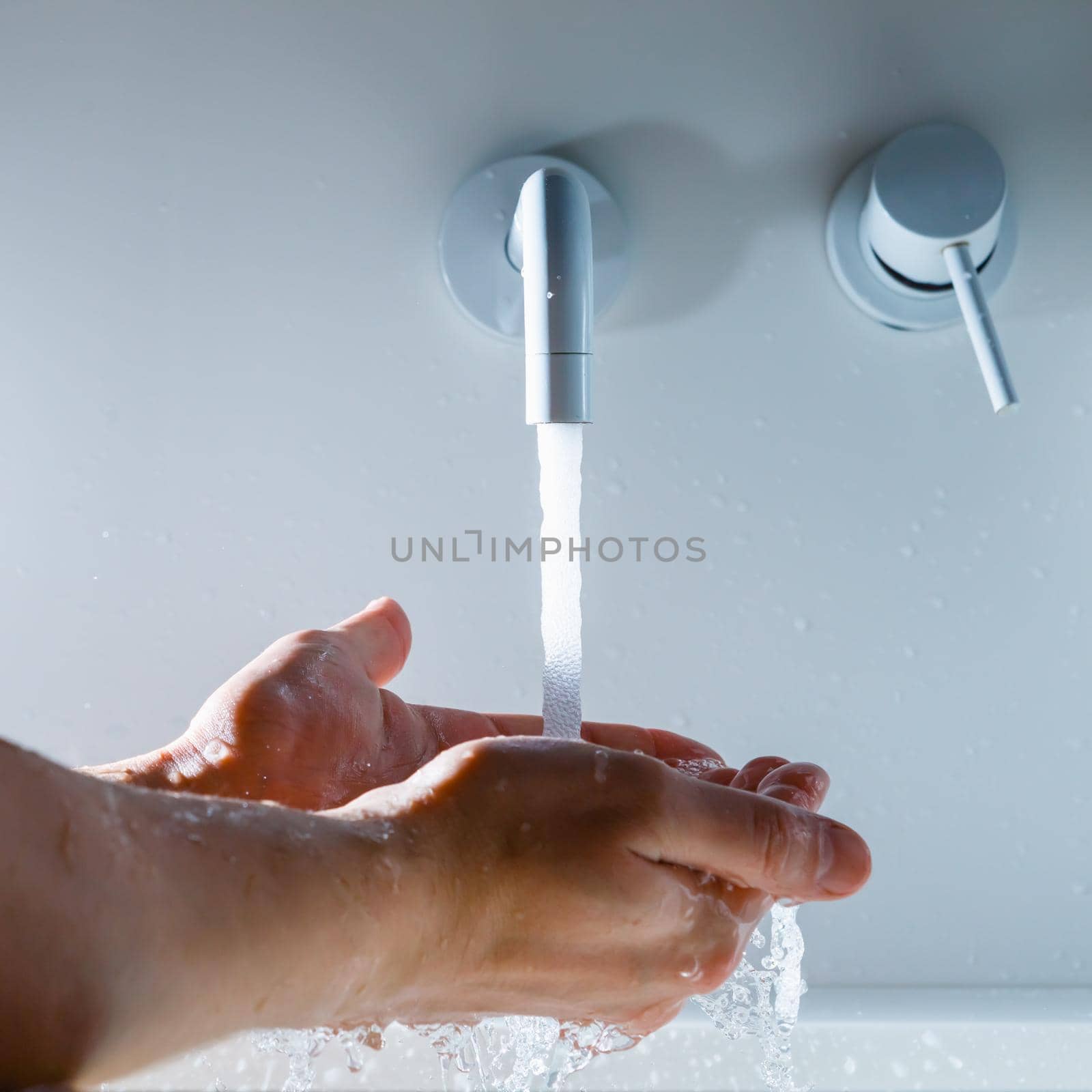 hands under the faucet with flowing water