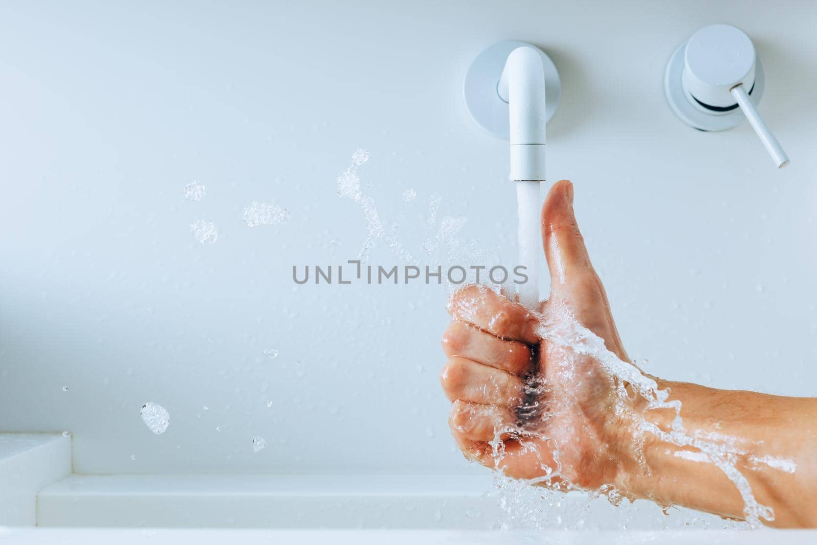 thumbs up hand under the faucet with flowing water, close-up view