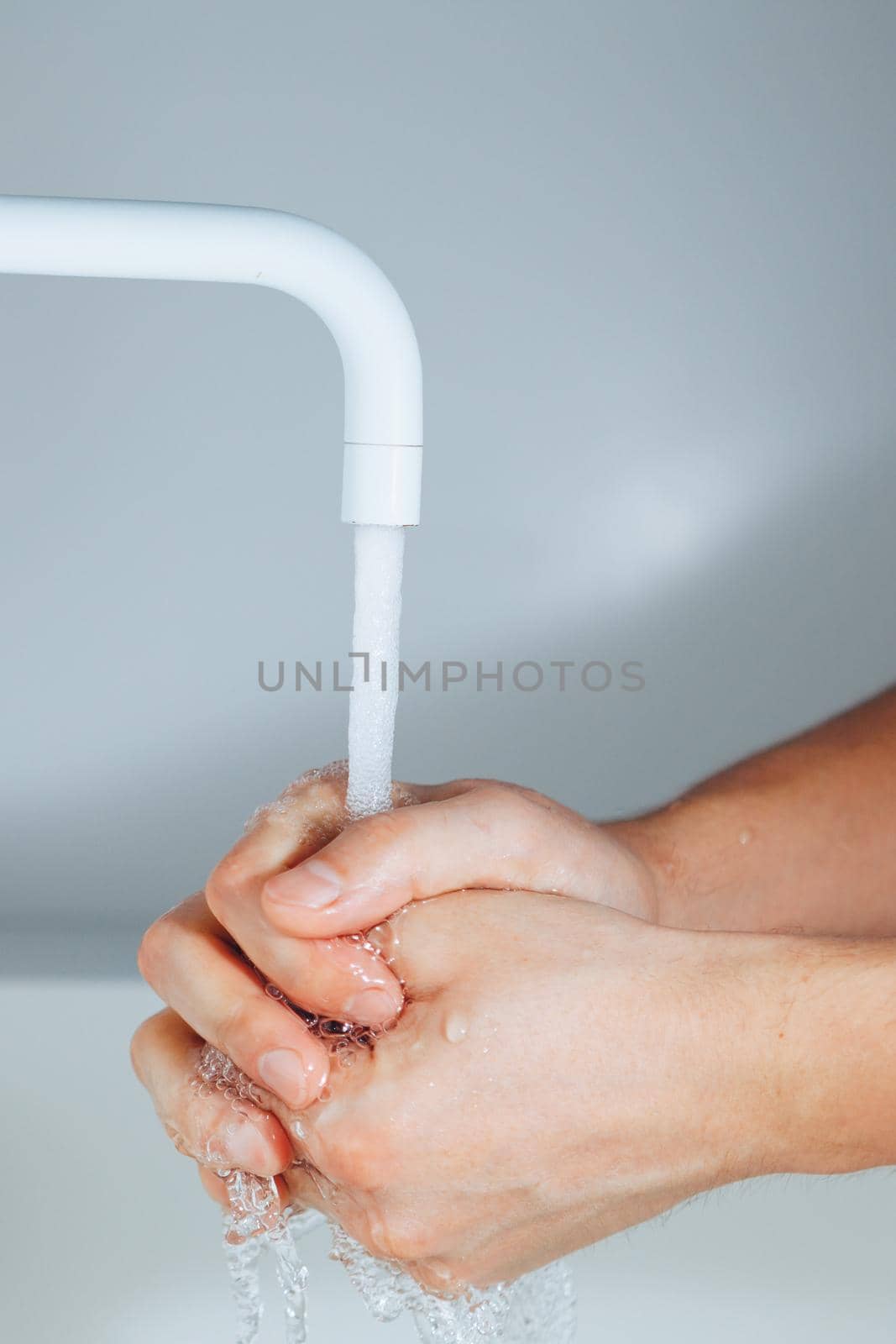 hands washing under the faucet in a bathroom
