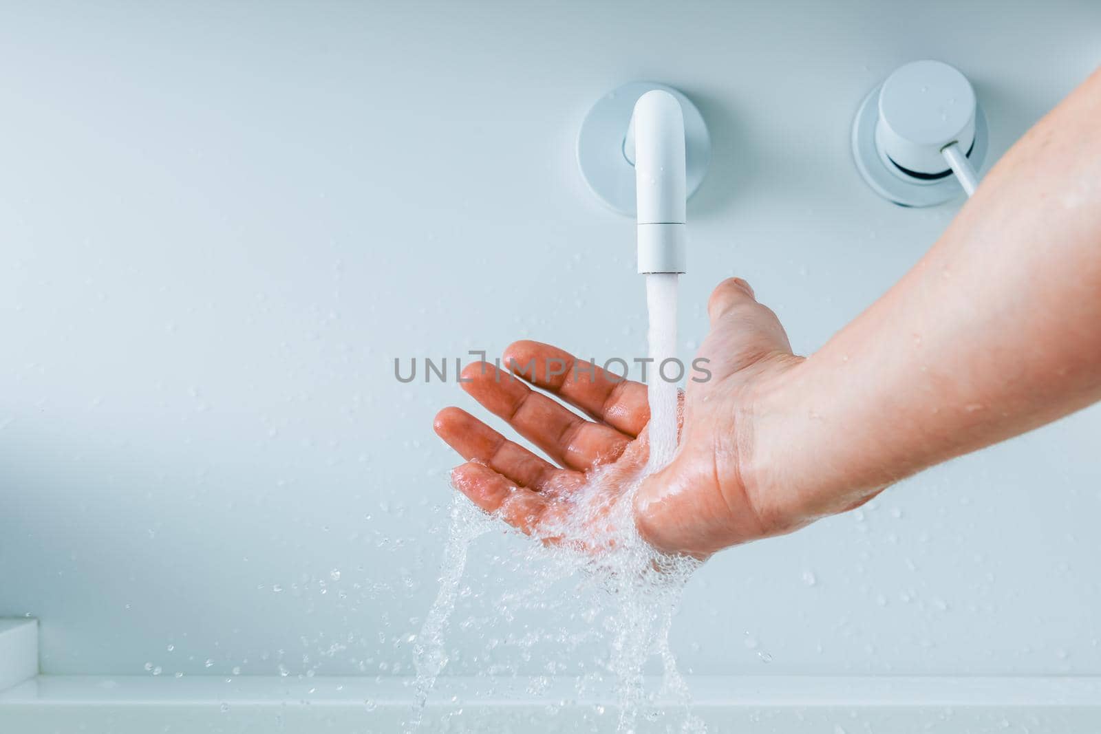 hand under the faucet with flowing water splash