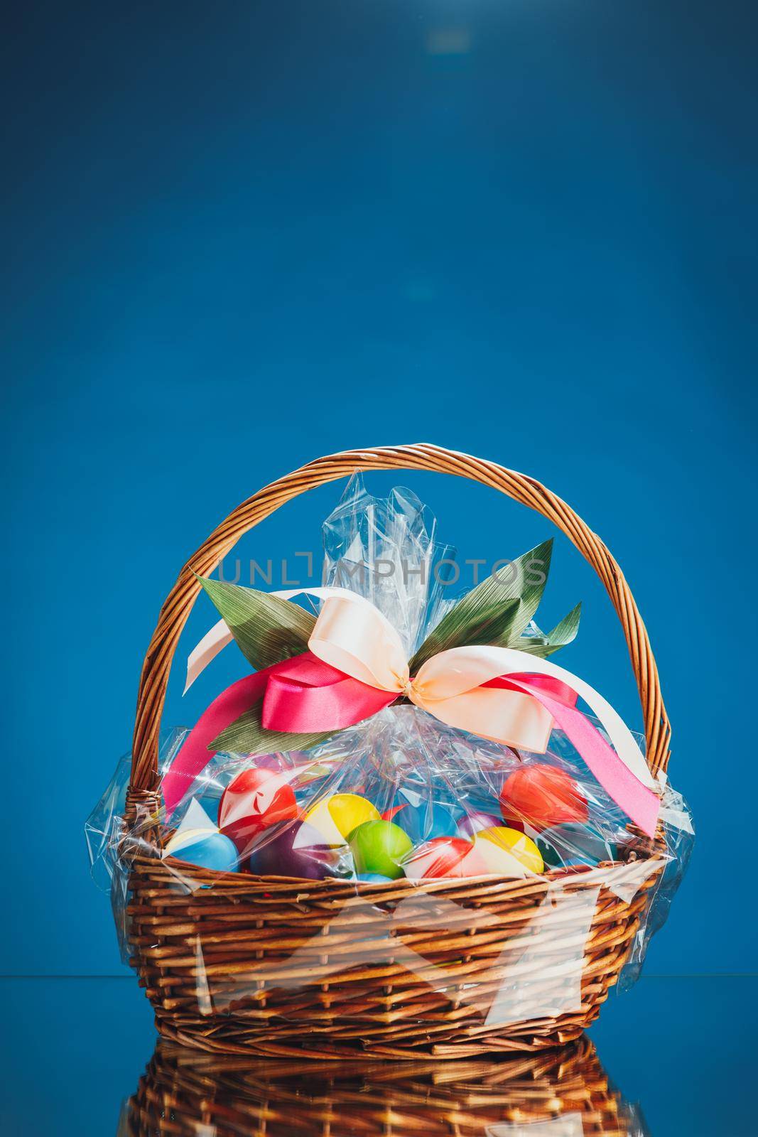 Easter gift basket with multicolor eggs, blue background