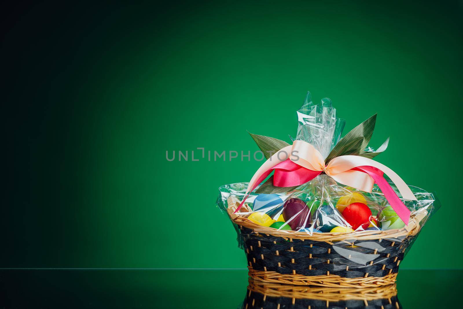 Easter gift basket with multicolor eggs, green background by nikkytok