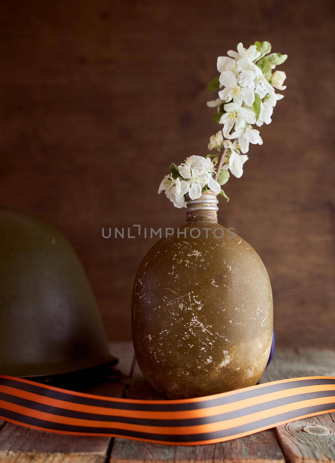 A sprig of an apple tree in a soldier's flask on a brown background. Photo by May 9. High quality photo