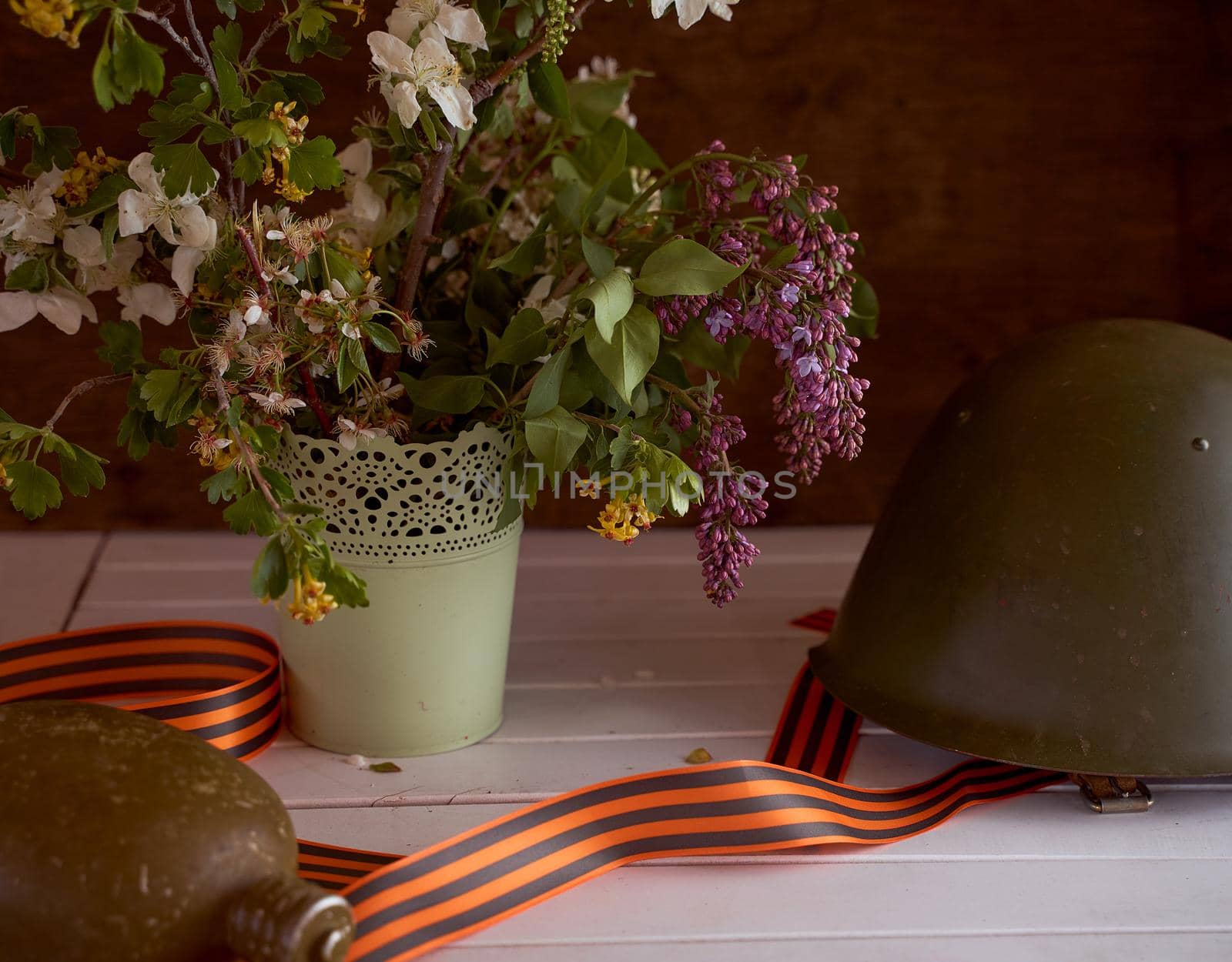 Composition to victory day. Soldier's helmet, ribbons and bouquet of spring flowers. High quality photo