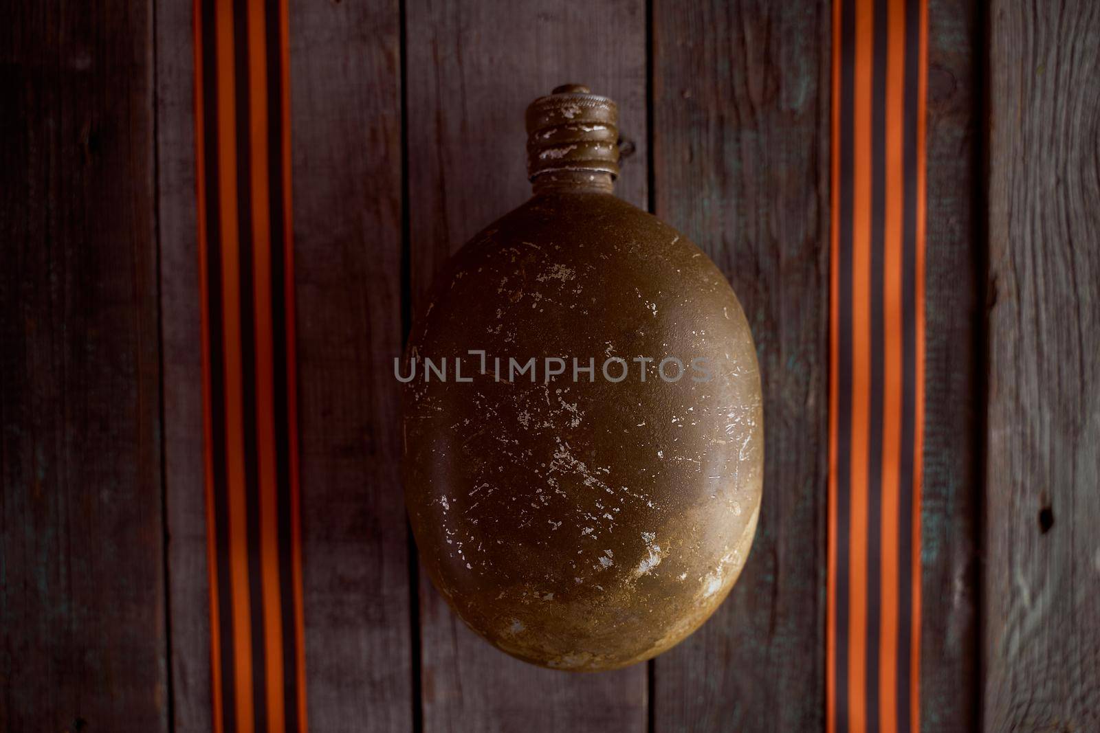 The soldier's flask lies between St. George's ribbons on a wooden table. High quality photo