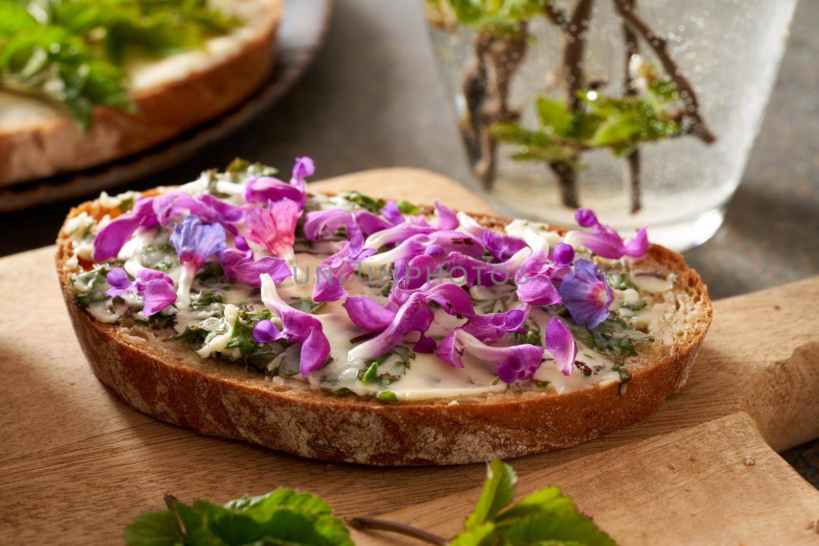Slice of bread with spring wild edible plants - young ground elder leaves, purple dead-nettle and lungwort flowers by madeleine_steinbach