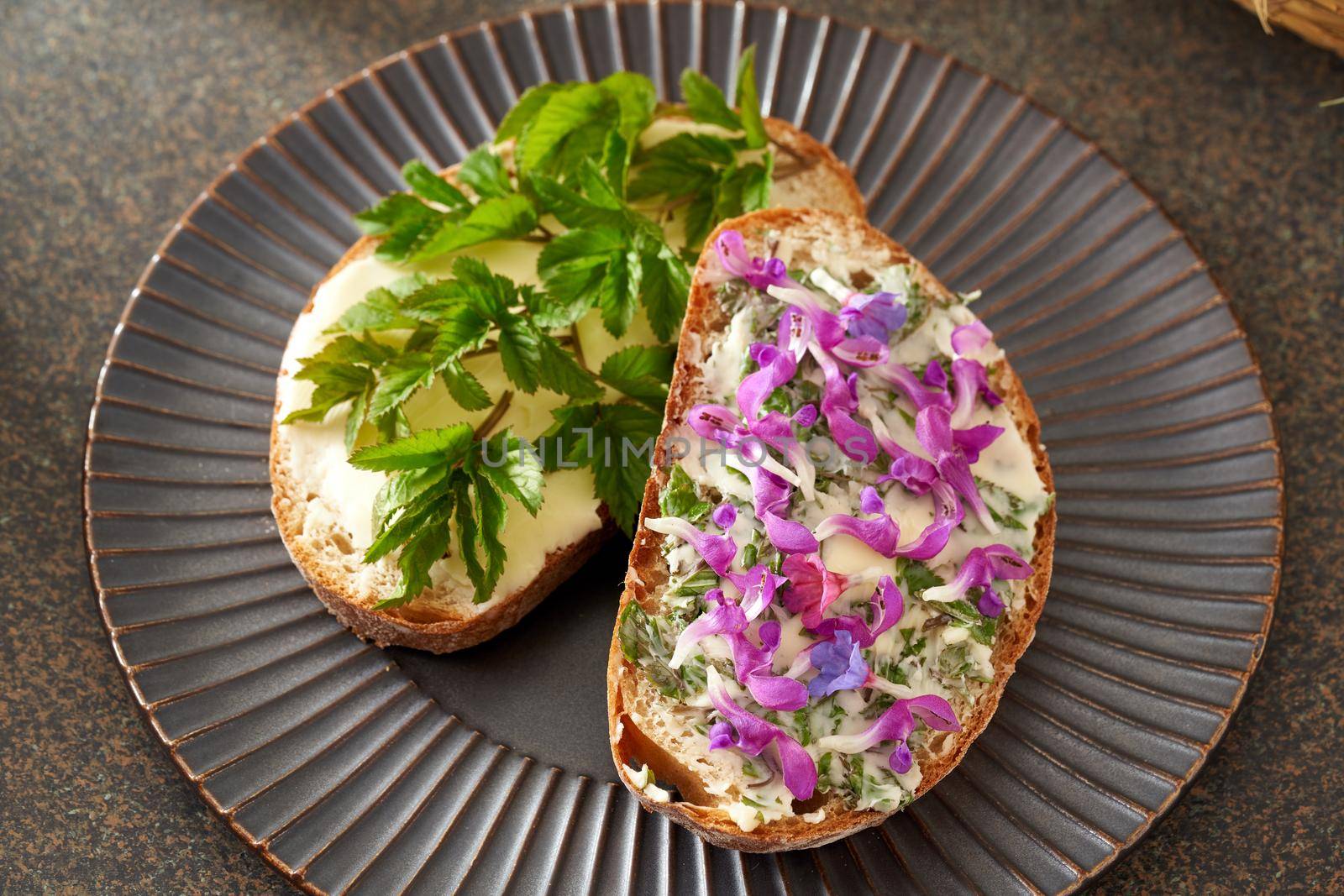 Two slices of bread with wild edible spring plants - goutweed leaves, purple dead-nettle and lungwort flo by madeleine_steinbach