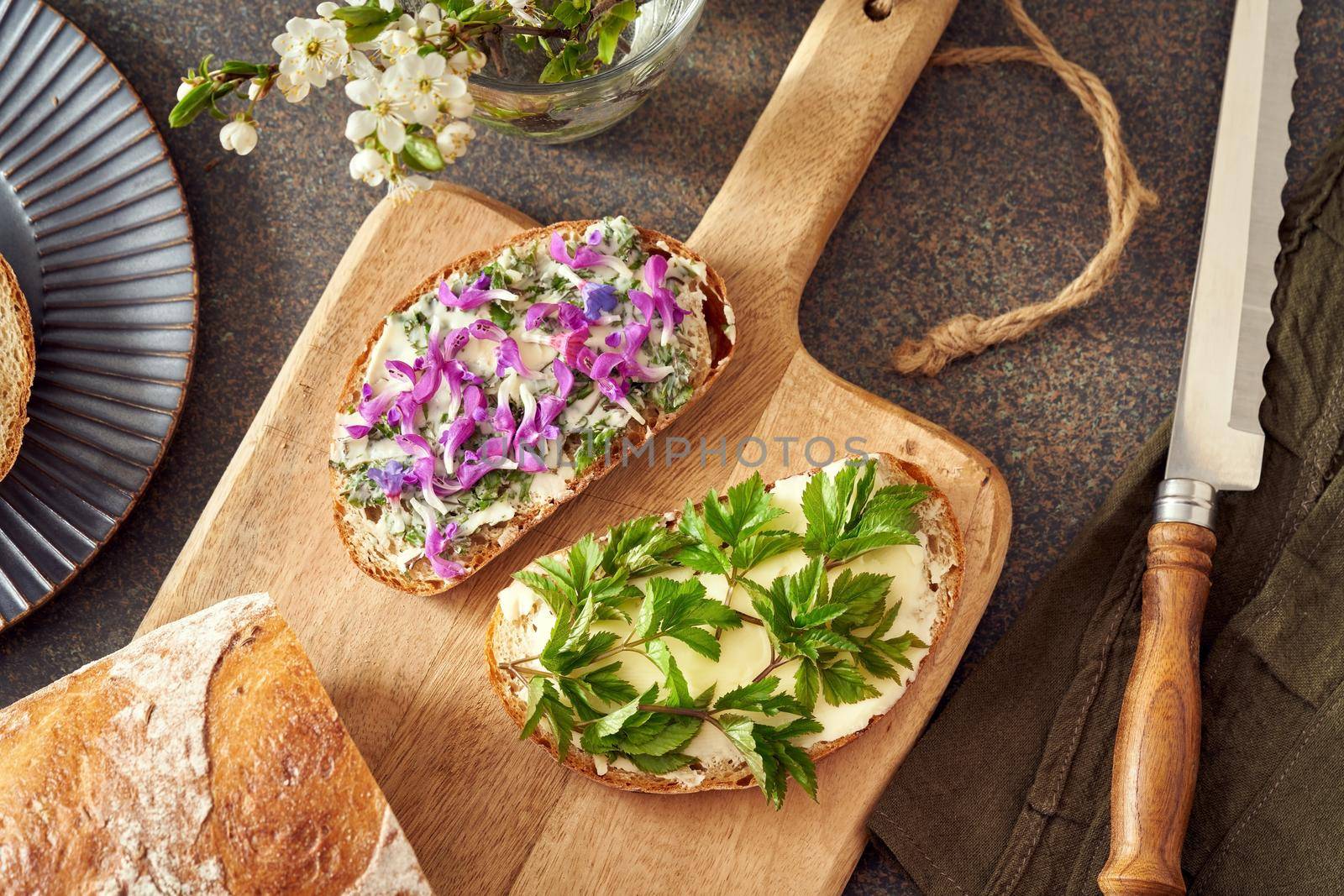 Sourdough bread with wild edible spring plants - young leaves of ground elder, blossoms of purple dead-nettle and lungwort