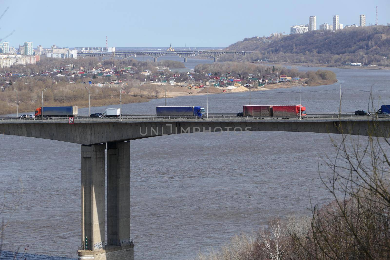 Large trucks drive over the bridge over the river in the city. High quality photo