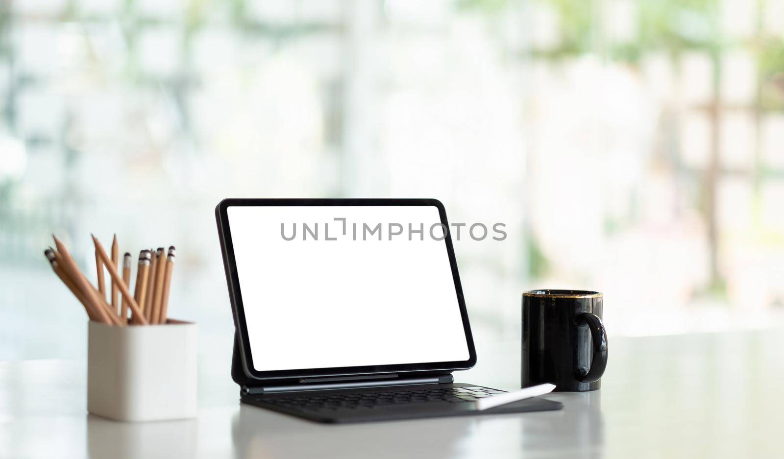 Mock up digital tablet with blank white screen on workplace at office