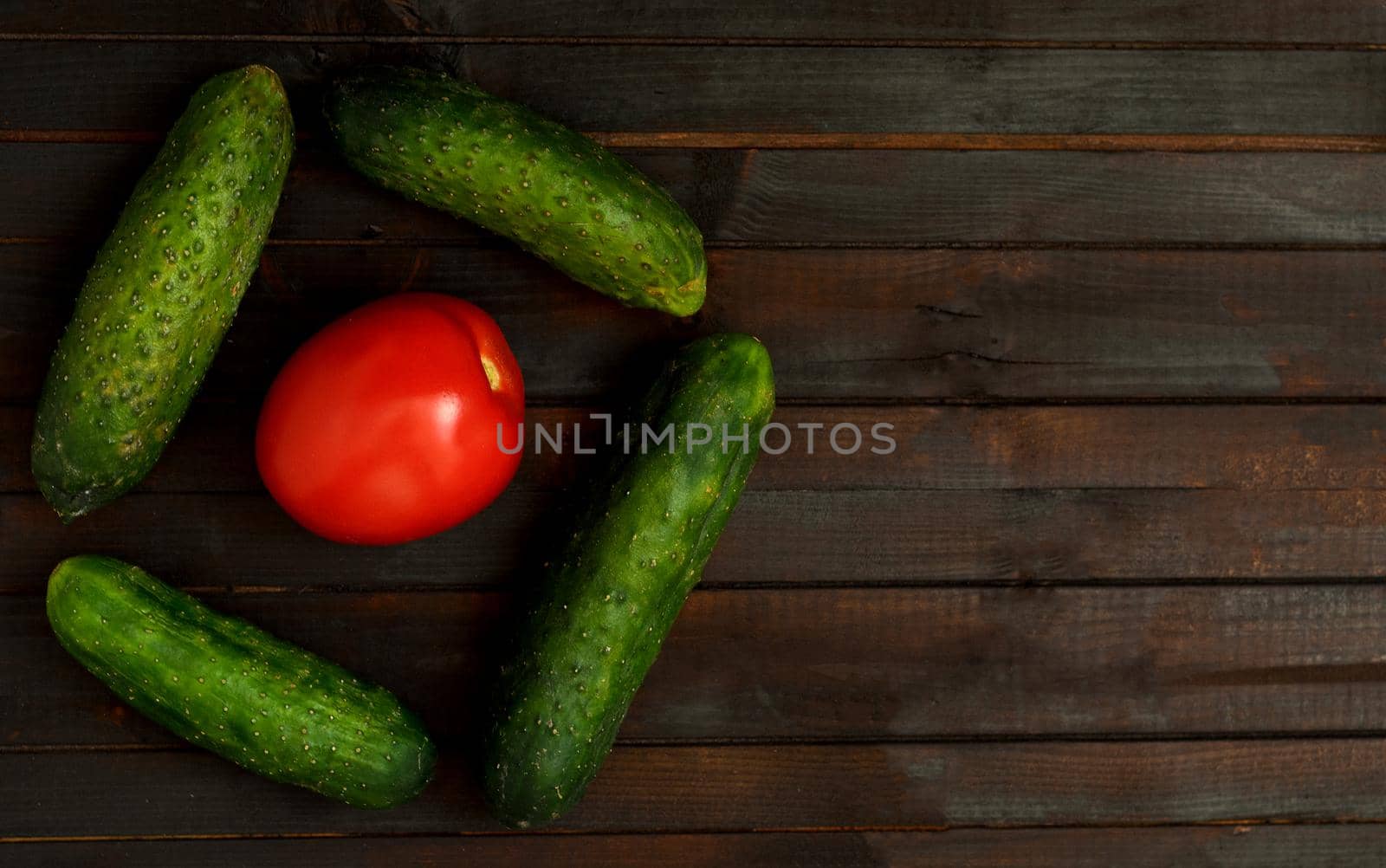 Food background with one tomato and cucumbers vegetables, copyspace.Top view.Vegan diet concept.