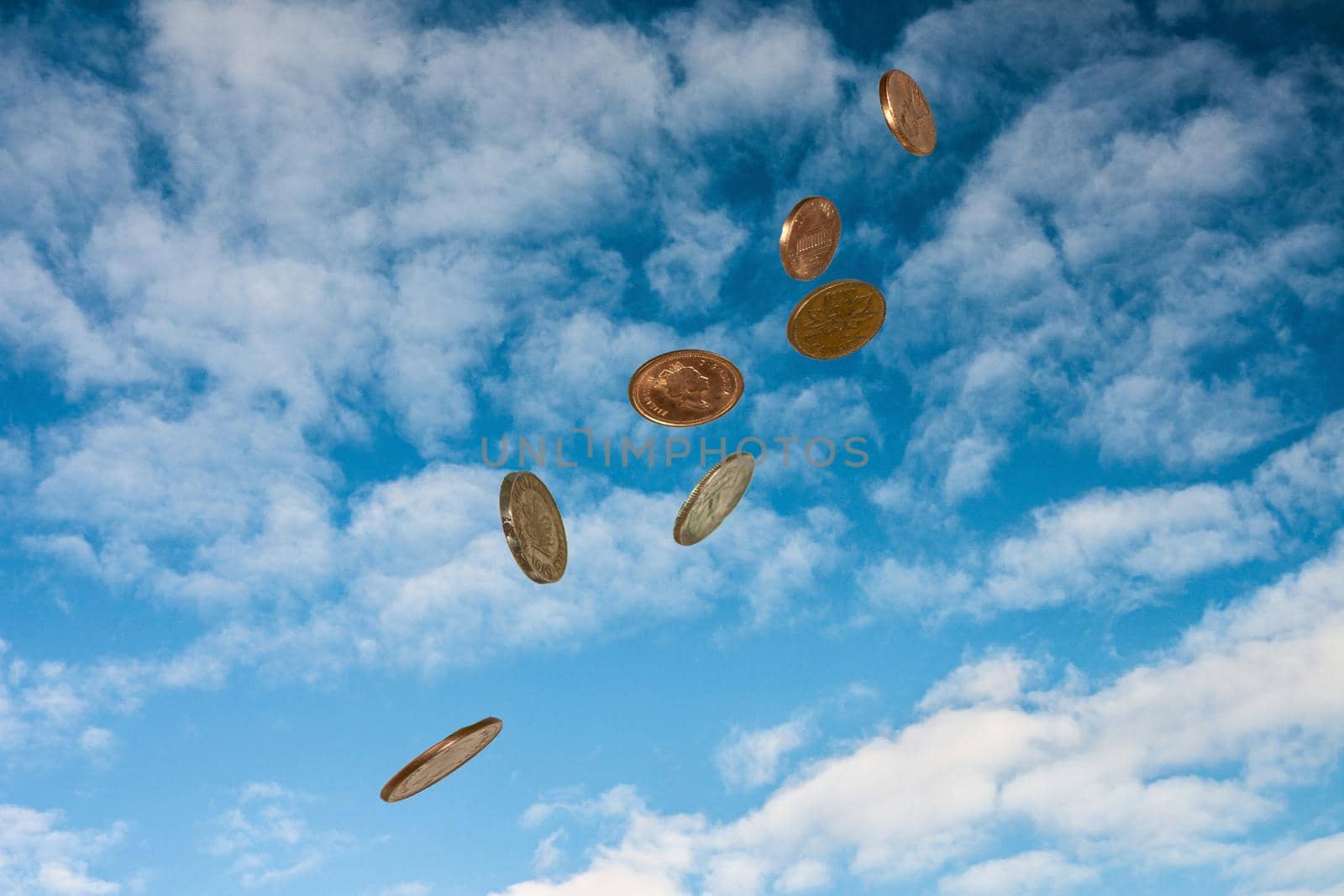 Coins falling from the sky against a background of white clouds