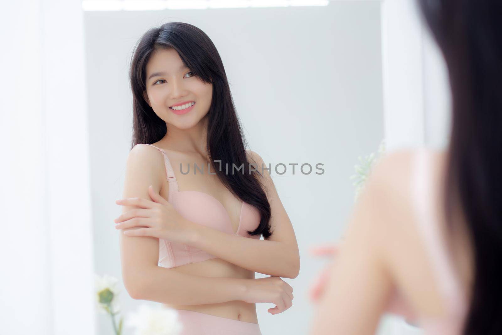 Beautiful sexy young asian woman look mirror applying cream on shoulder and message, beauty girl applying body lotion skin care for health and soft hydration, treatment and cosmetic with moisturizer.
