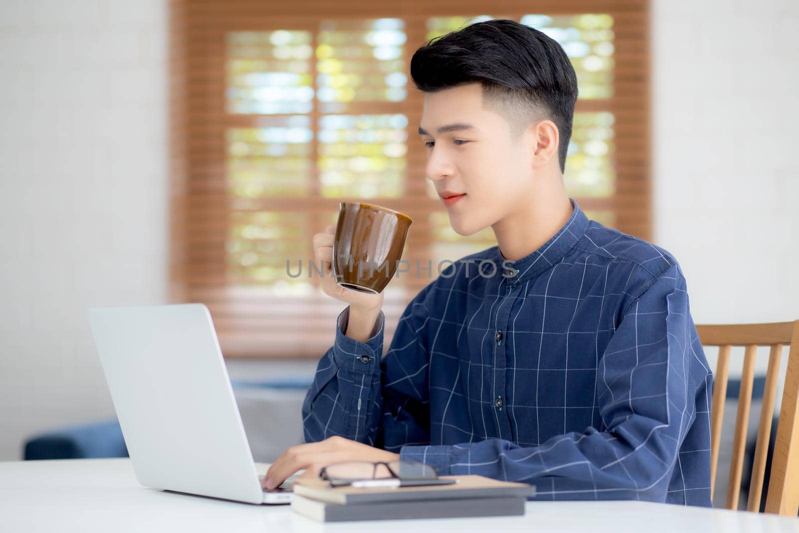 Young business man working from home with laptop computer on desk, freelance male sitting stay home using notebook for communication and relax on table, entrepreneur in startup business, new normal.