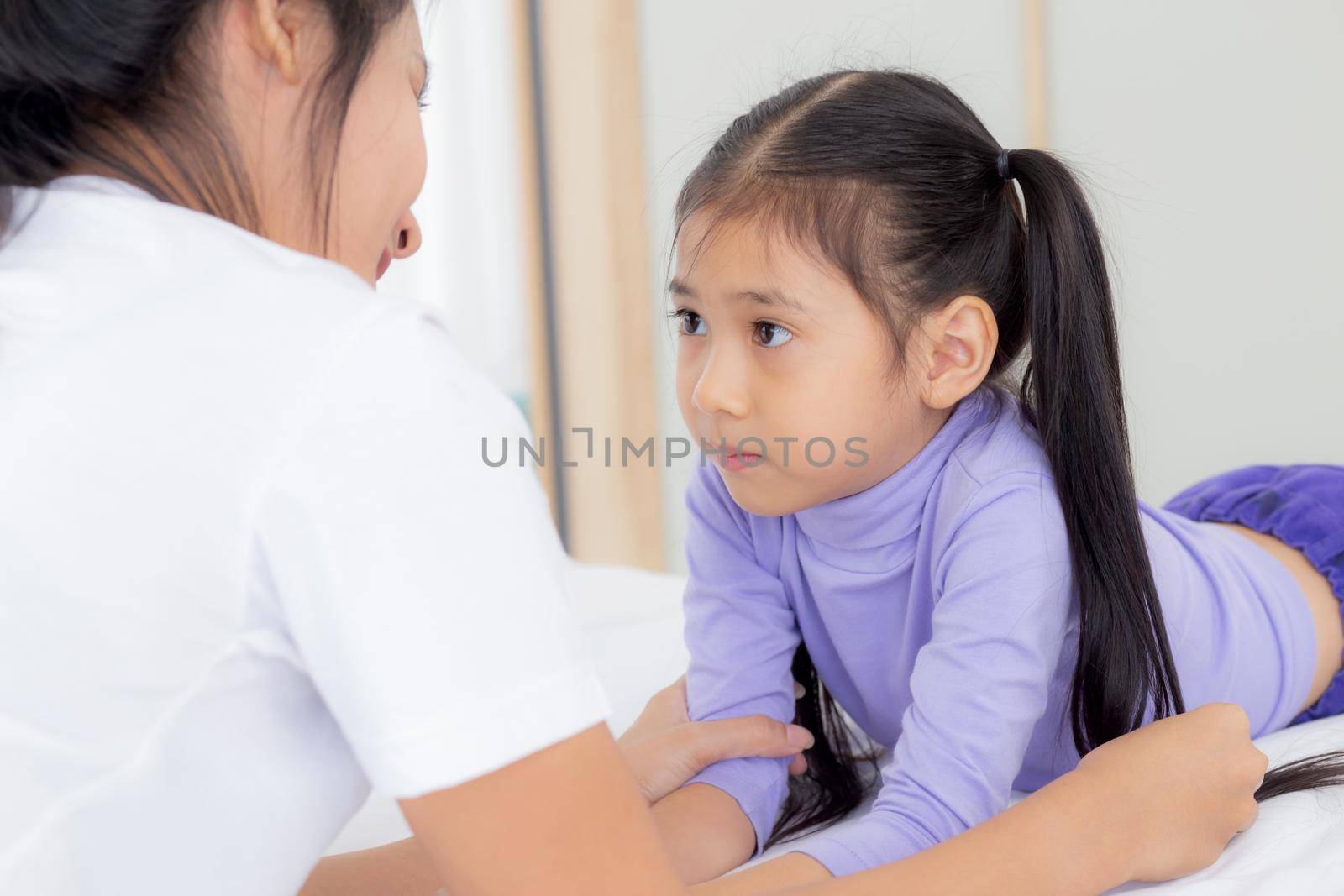 Young asian mom and daughter smiling and eye contact together with care in room, face of mother and girl looking eye with relationship and bonding, emotion and expression, family and love concept.