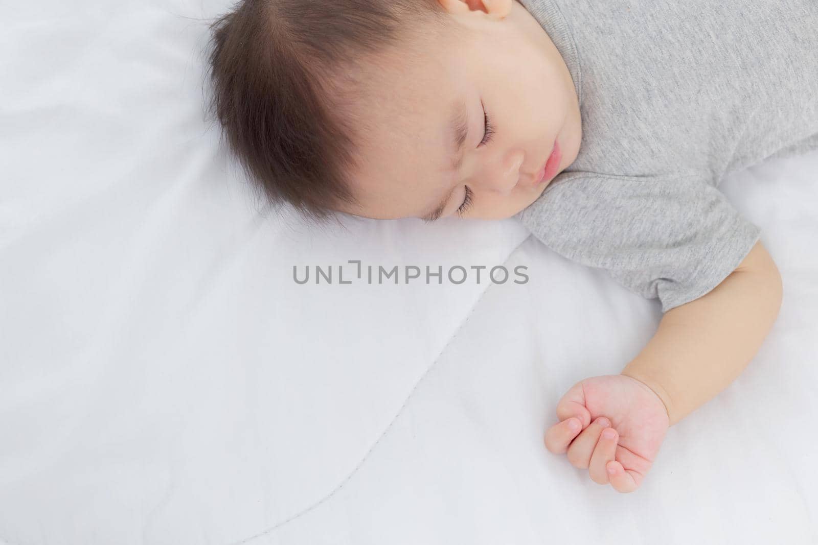 Portrait of asian little baby girl sleeping on bed in the bedroom at home, newborn napping with cozy and relax, infant innocence in bedtime, happy toddler cute, growth of child and emotion, indoors.